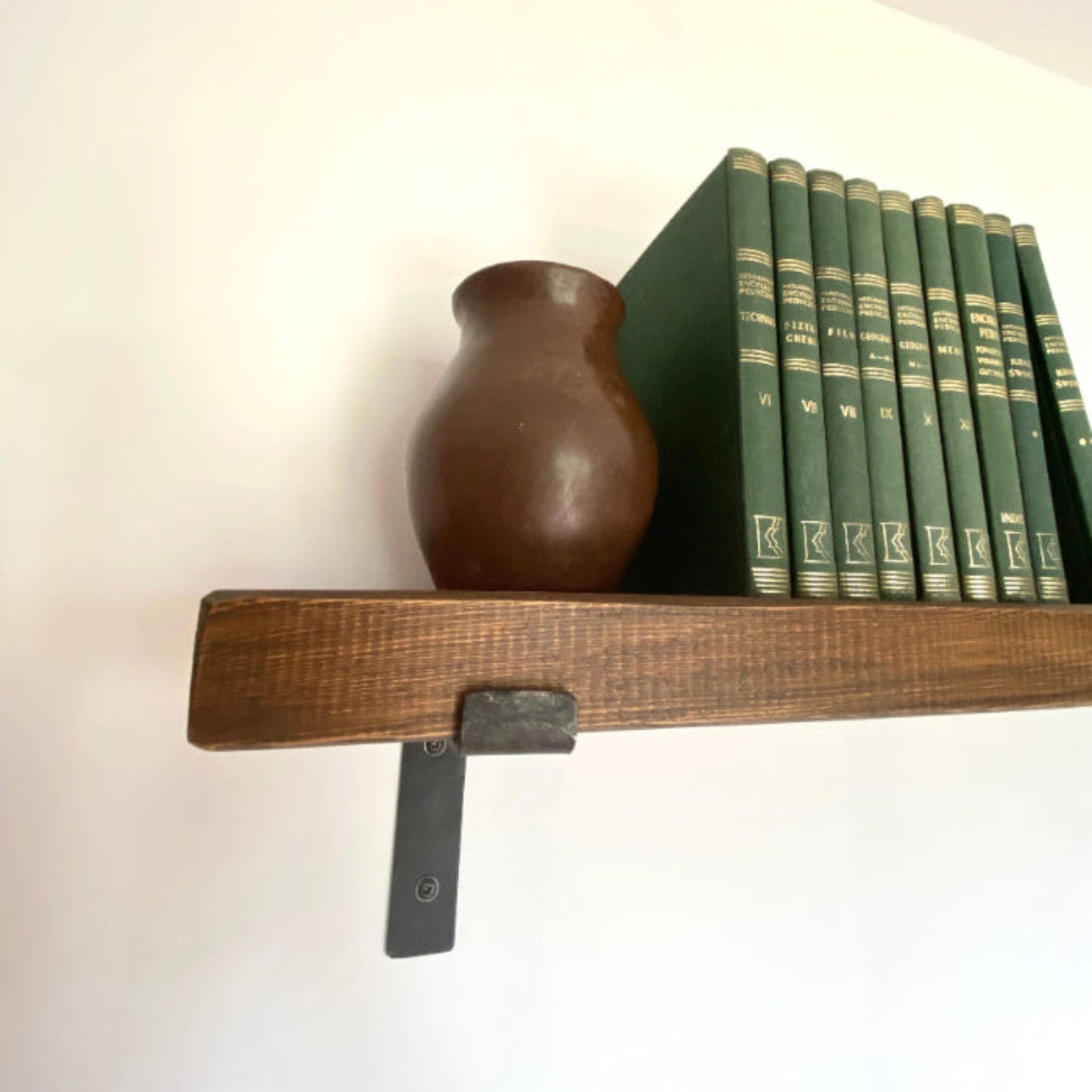 Wooden shelf with a vase and books against a white wall