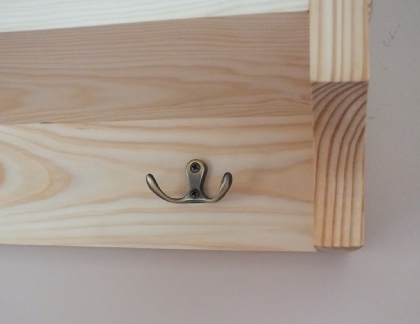 Wooden frame with a metal hook on a plain background