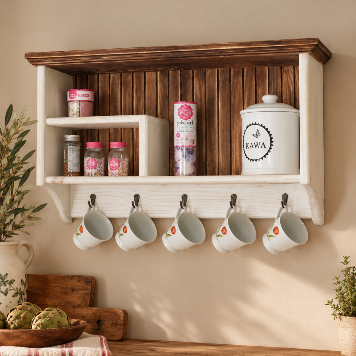 A wall-mounted wooden kitchen organizer shelf with a white lower rack holding five white mugs on hooks, plus shelves and jars above. The scene is styled in a warm kitchen setting with plants, a cutting board, and countertop items.