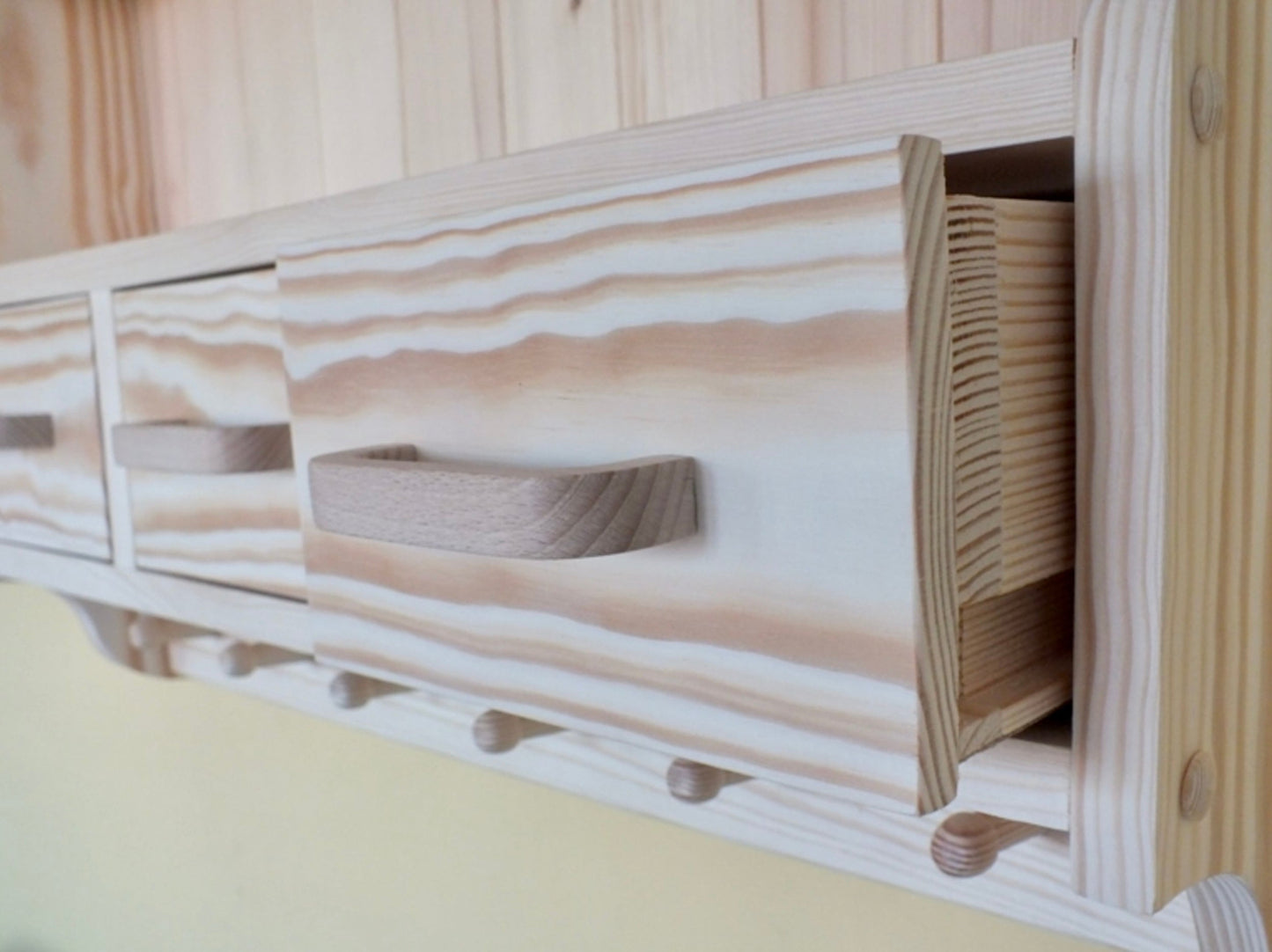 Wooden headboard with storage compartments and hooks against a wooden wall.