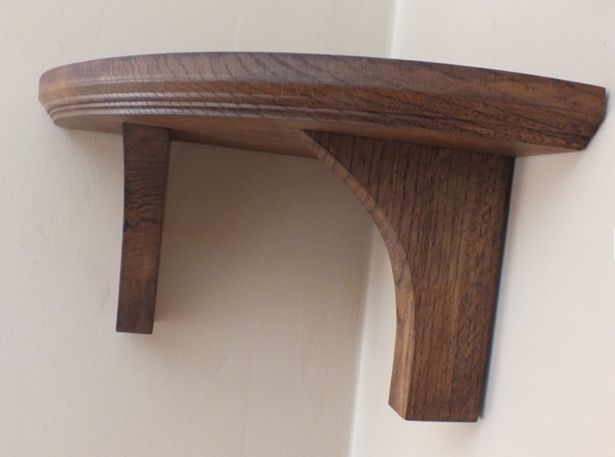 A curved wooden shelf with two support brackets, shown mounted against a plain beige wall.