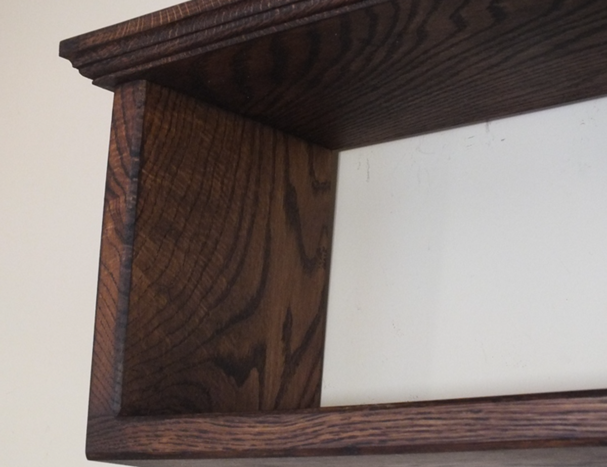 Close-up of a dark brown wooden shelf corner showing the wood grain and finish against a plain off-white background.