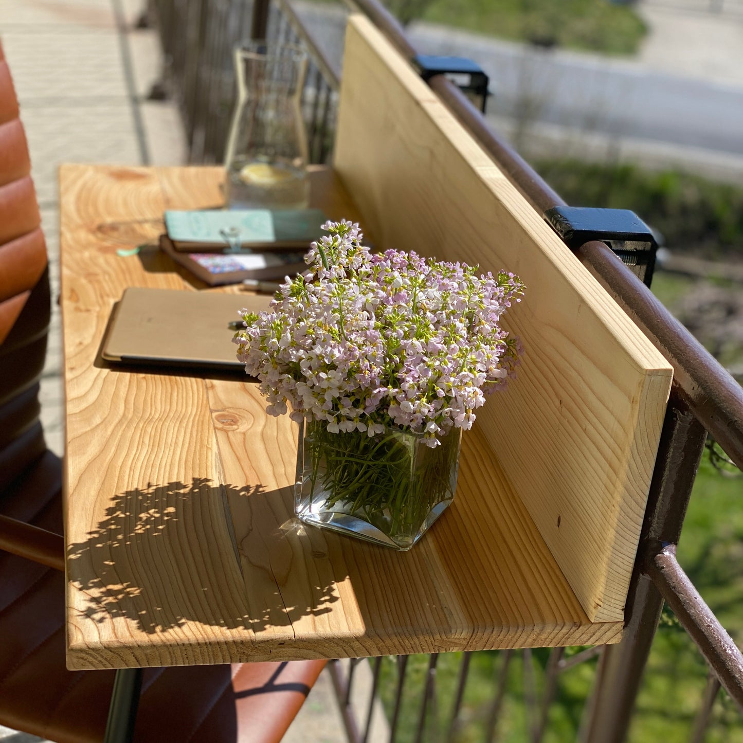 Wooden table with a vase of flowers on a balcony