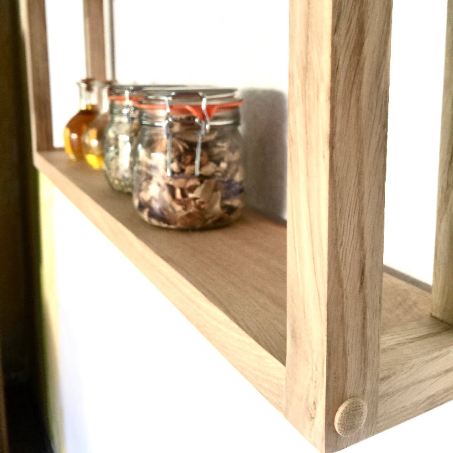 Wooden shelf with glass jars containing various items on a white background