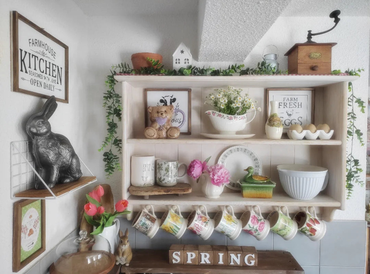 Decorative kitchen shelf with mugs, flowers, and kitchen-themed decor.