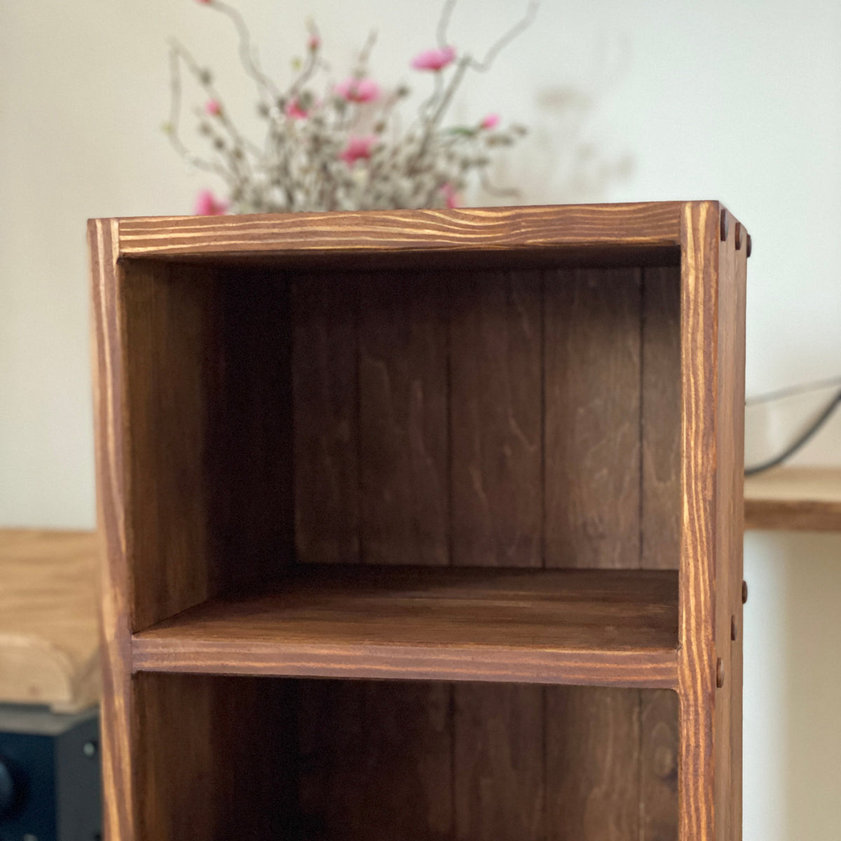 A rustic wooden two-tier bookcase with a dark brown finish and visible wood grain, shown against a neutral indoor background.
