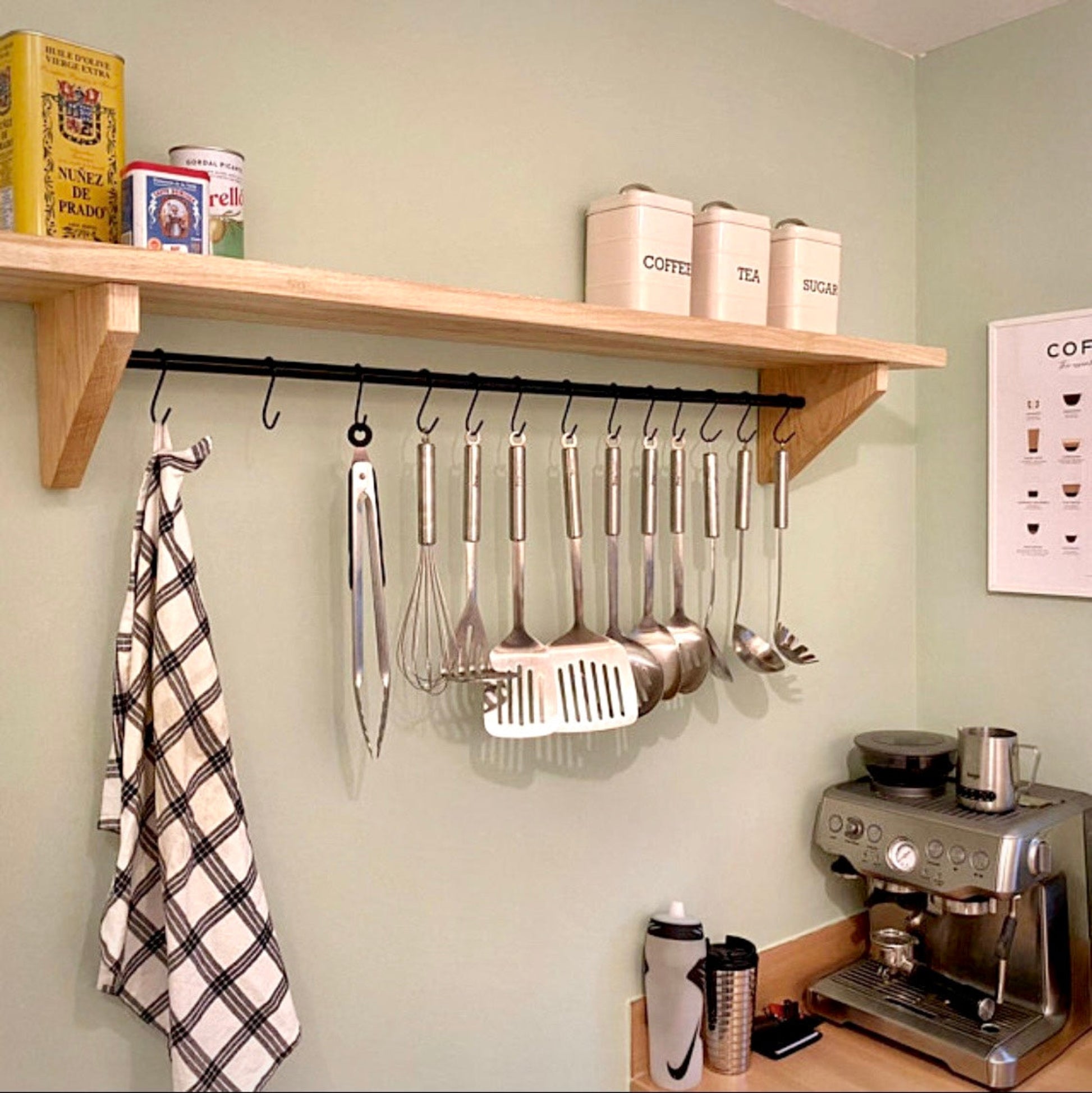 Kitchen setup with wooden shelf, hanging utensils, and coffee machine.