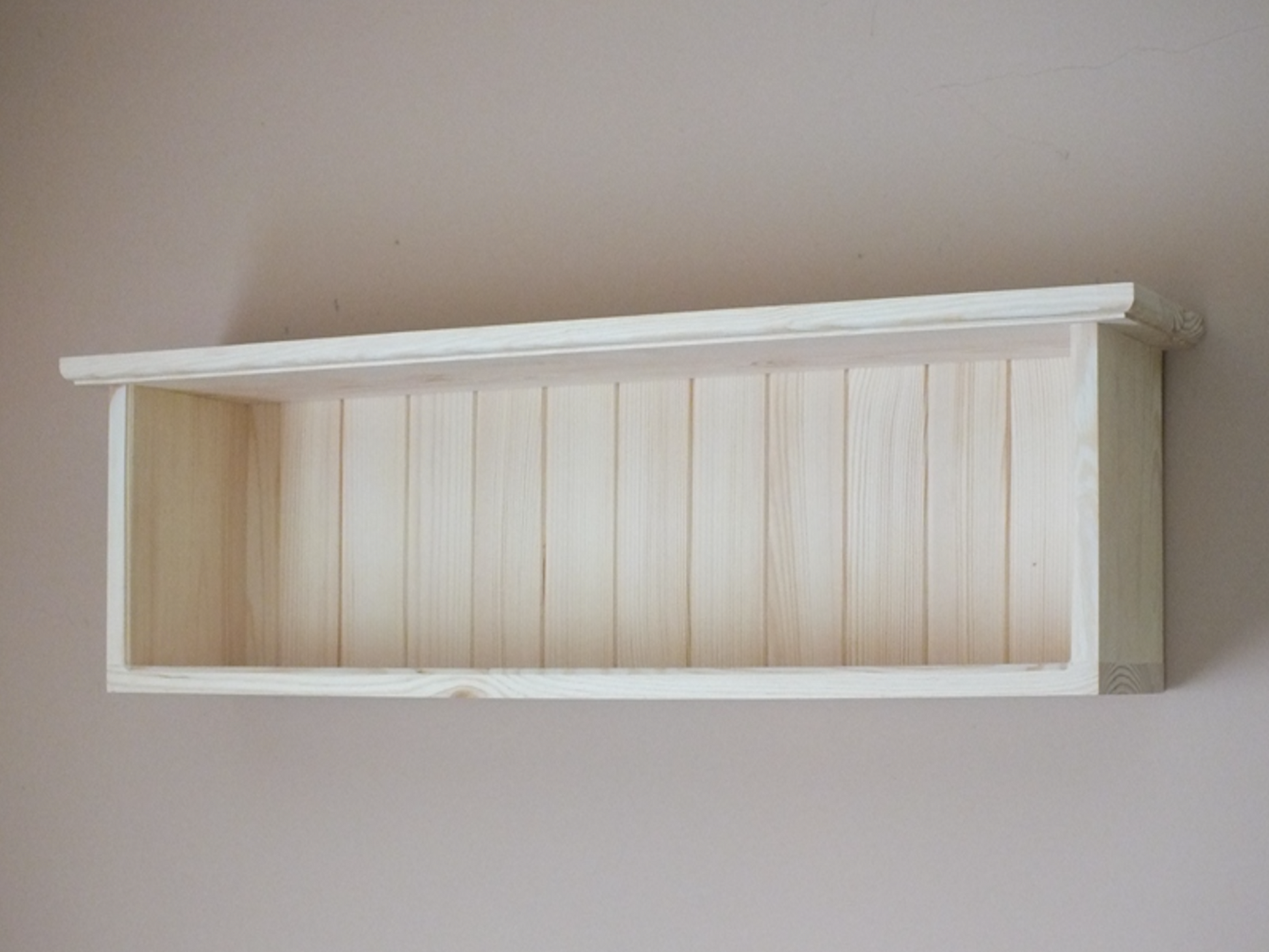 A natural pine wood, wall-mounted open compartment shelf with a single shelf and a visible grain pattern.