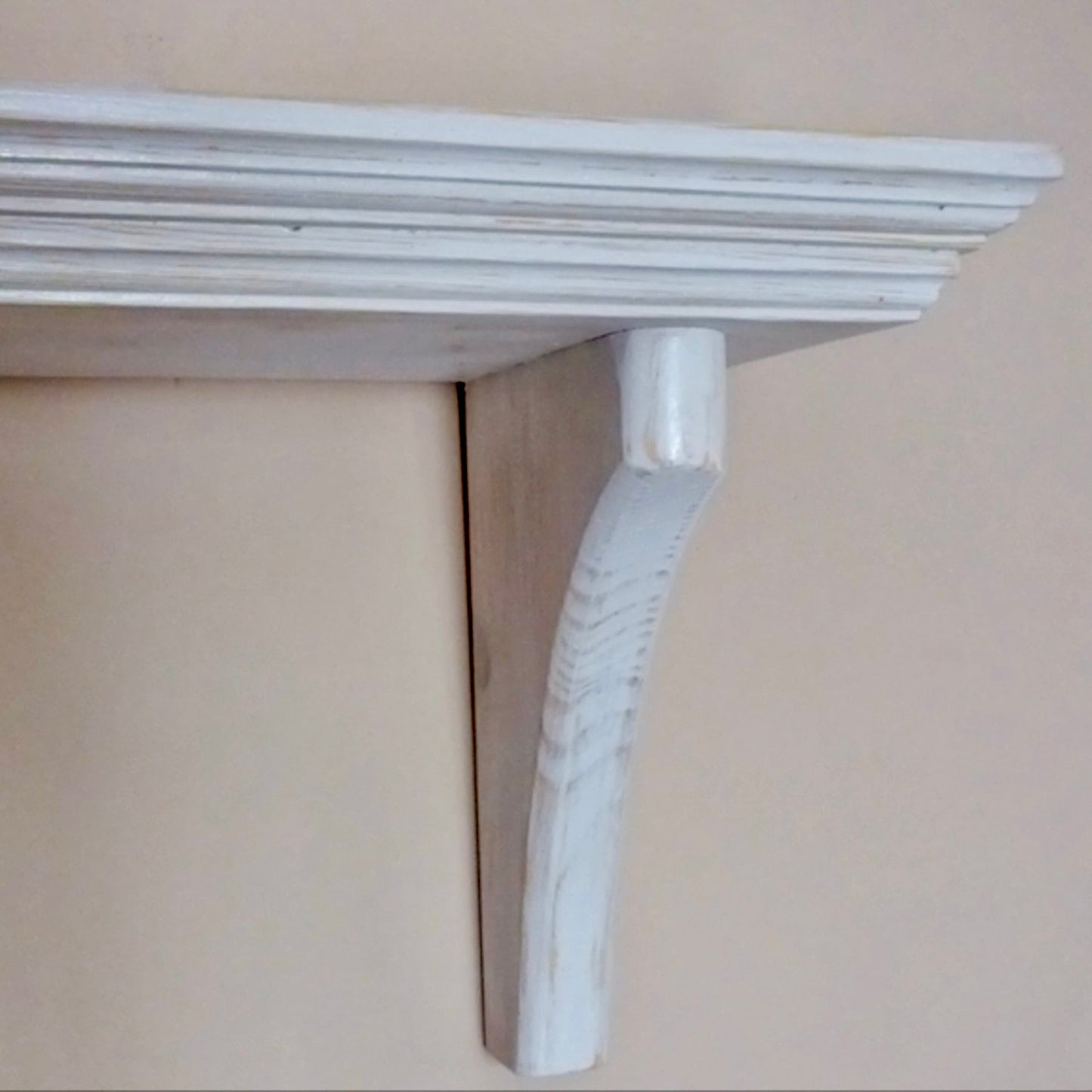 White decorative shelf bracket on a beige wall