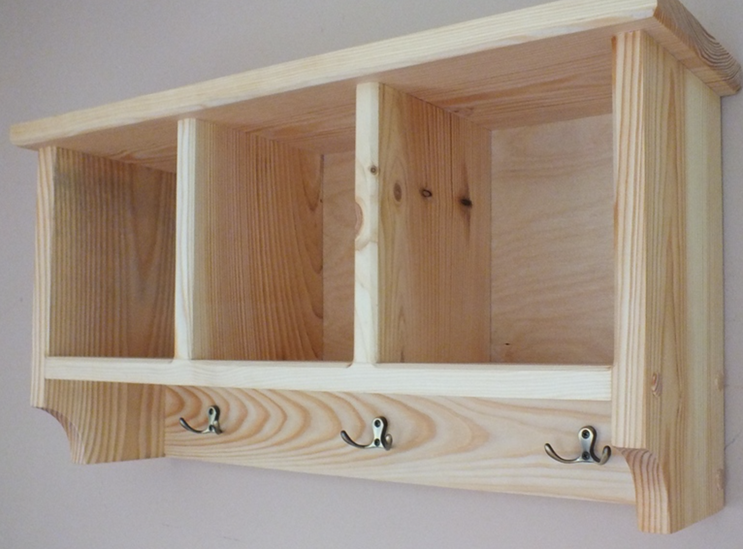 Wooden shelf with hooks on a plain background