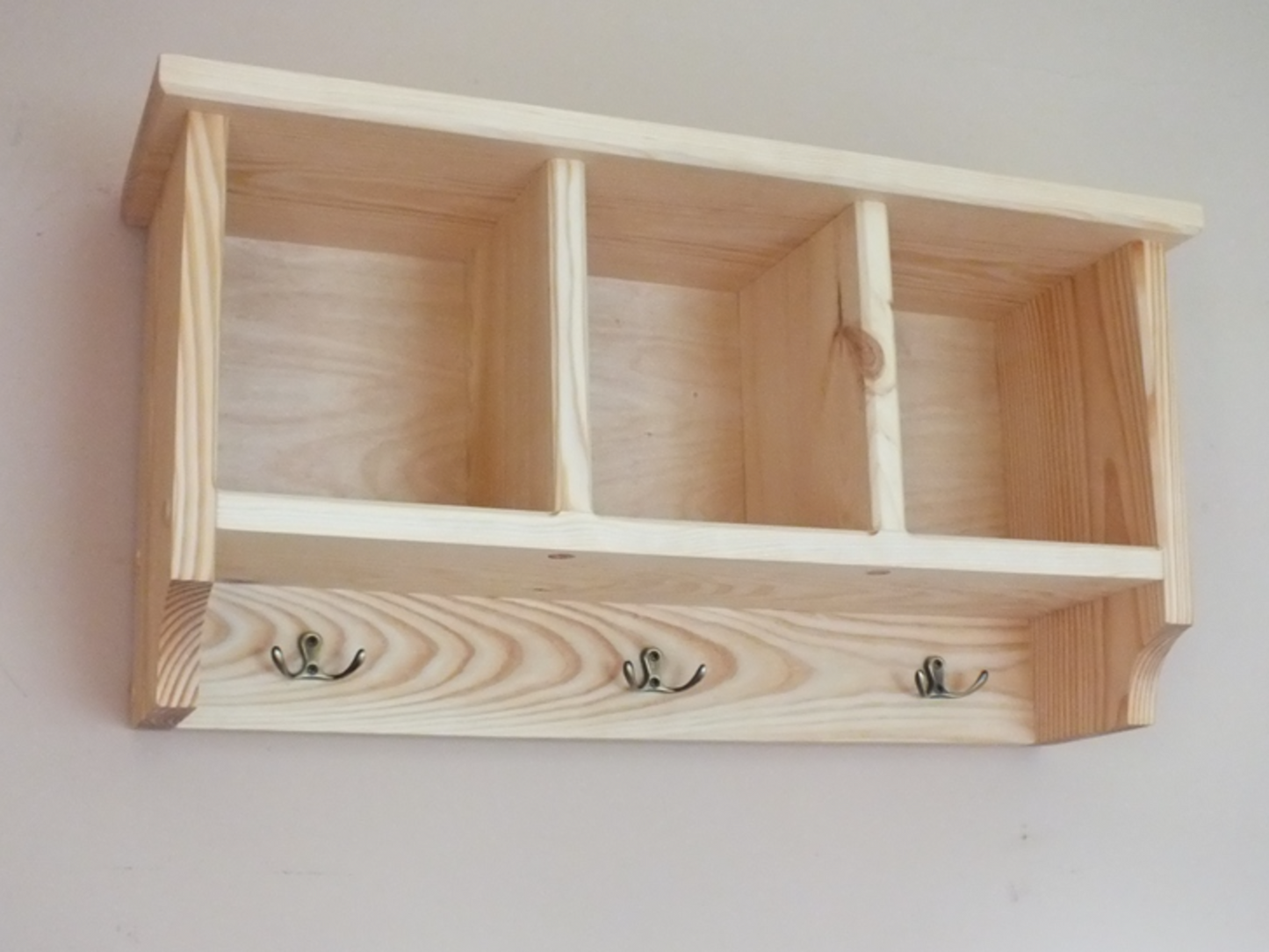 Wooden shelf with hooks on a plain background