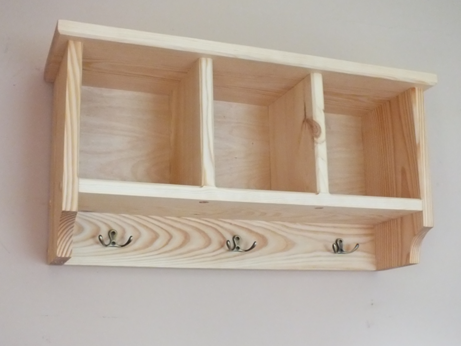 Wooden shelf with hooks on a plain background