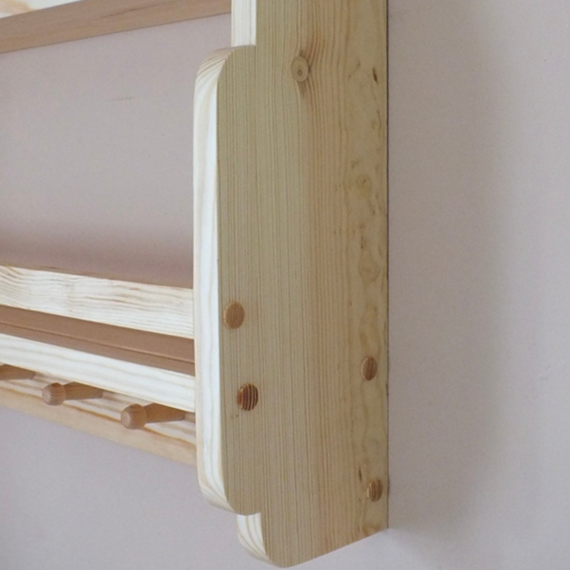 Wooden bunk bed with white mattress against a plain wall