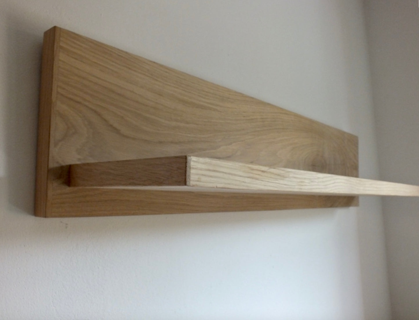 Wooden shelf mounted on a plain wall