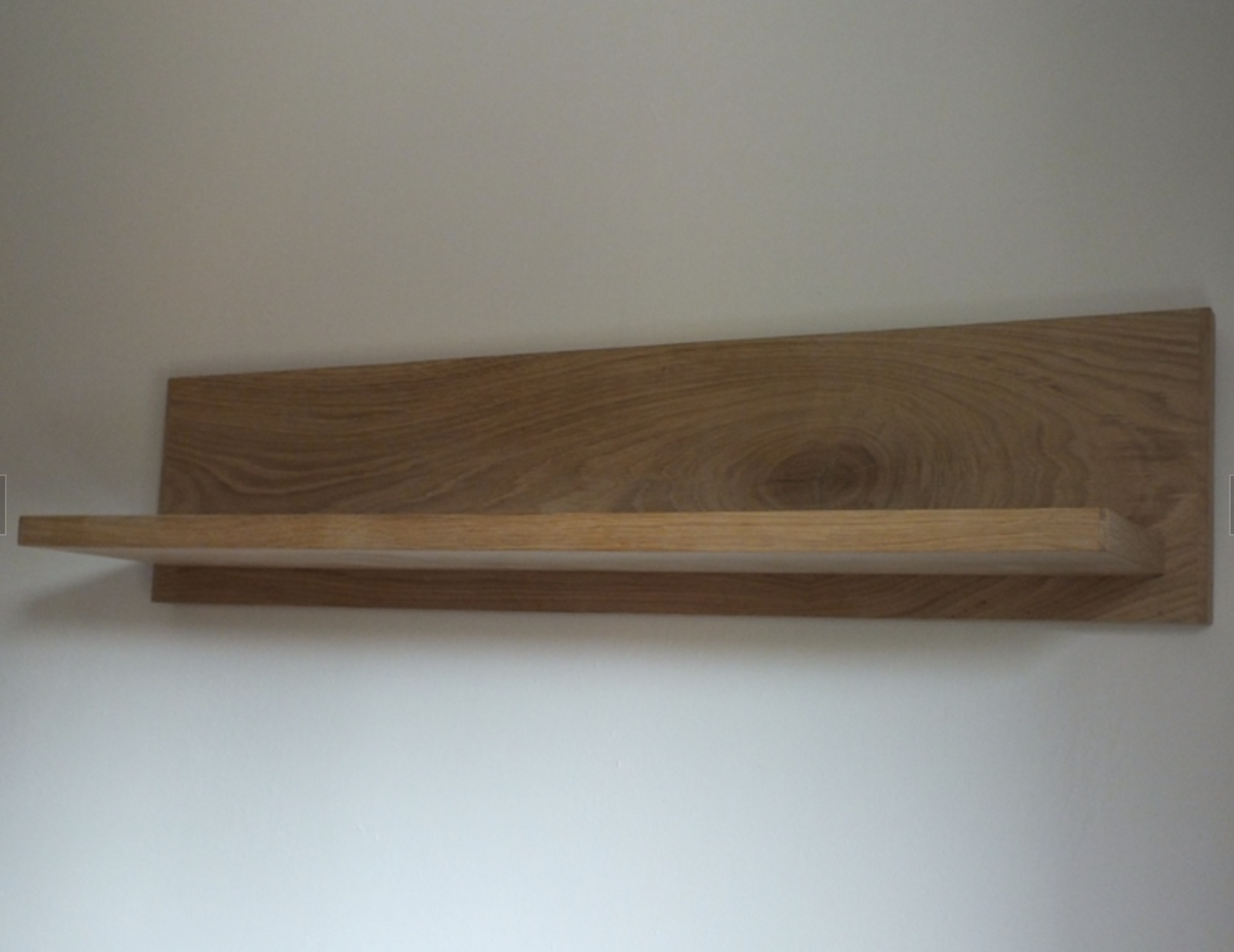 Wooden shelf mounted on a white wall
