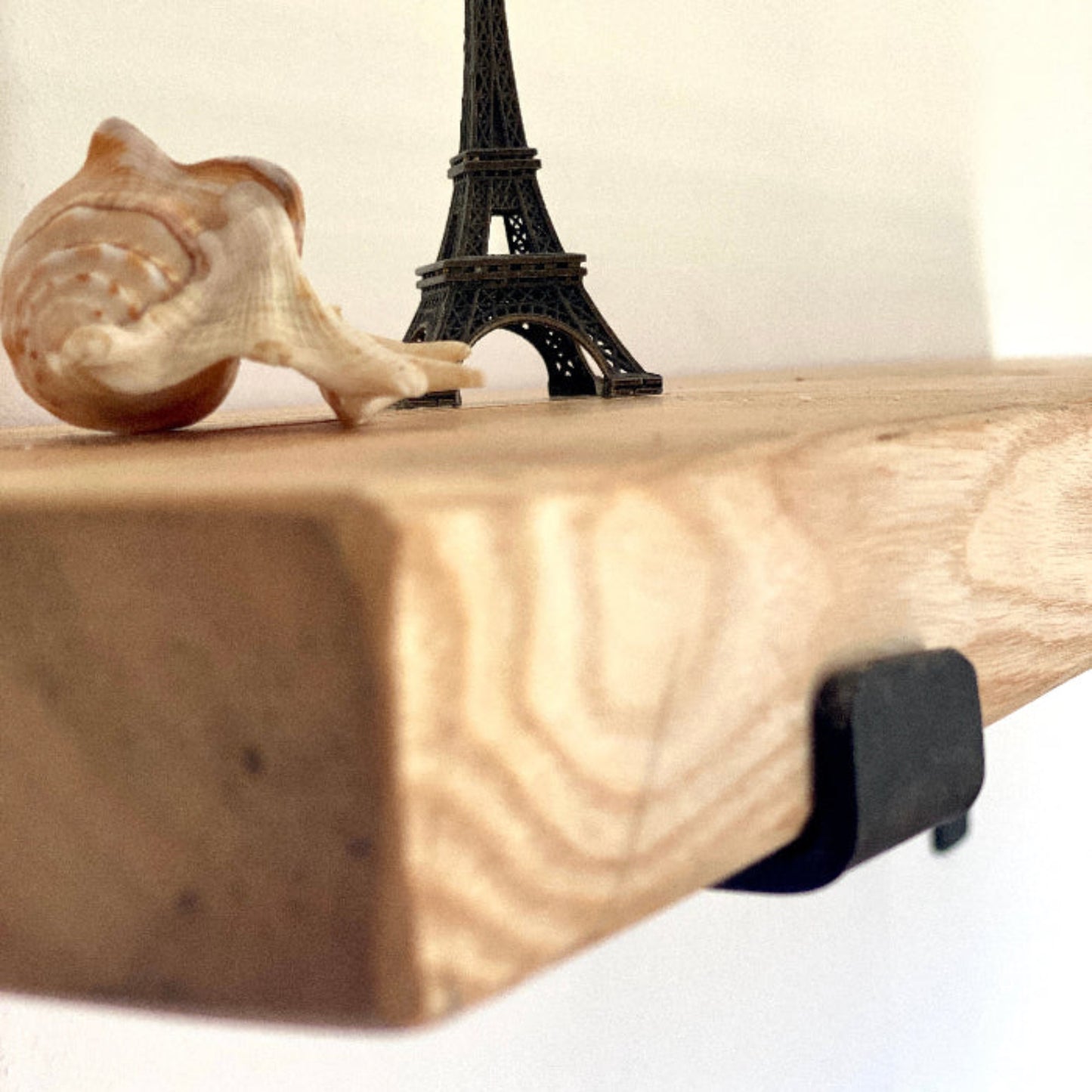 Wooden shelf with a small Eiffel Tower figurine and a wooden snail on a white background