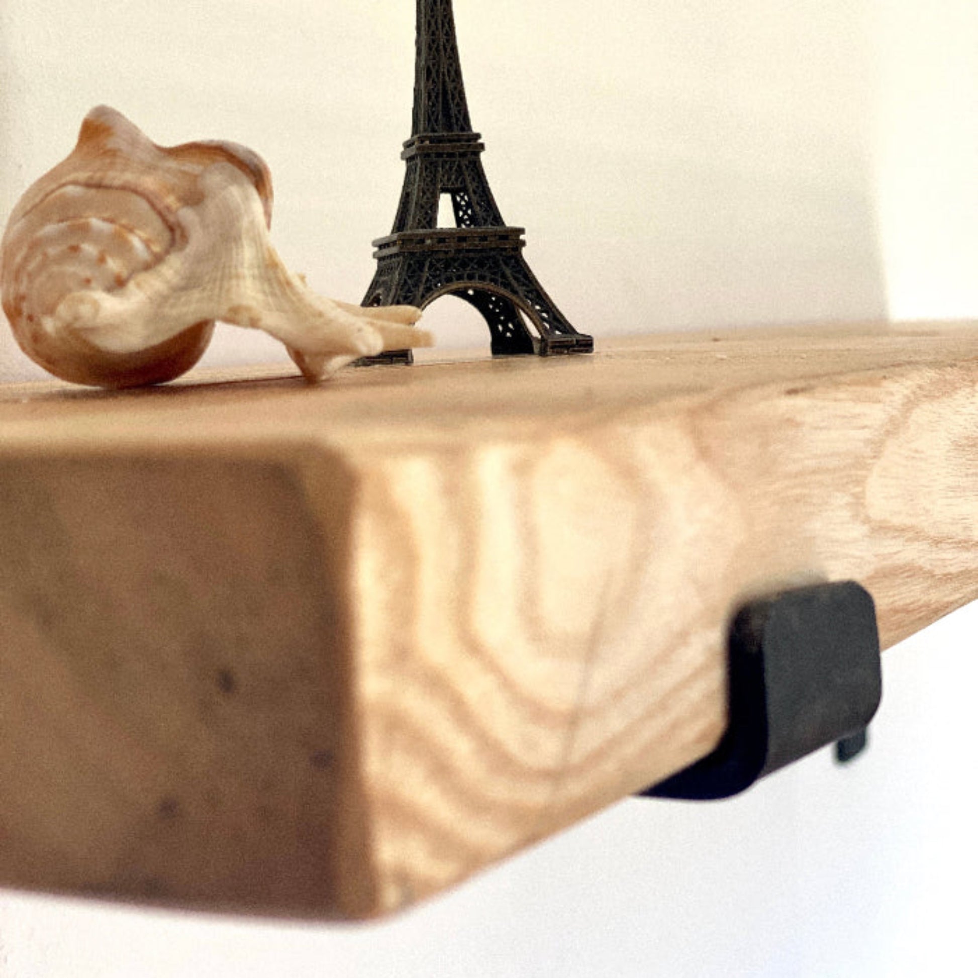 Wooden shelf with a small Eiffel Tower figurine and a wooden snail on a white background