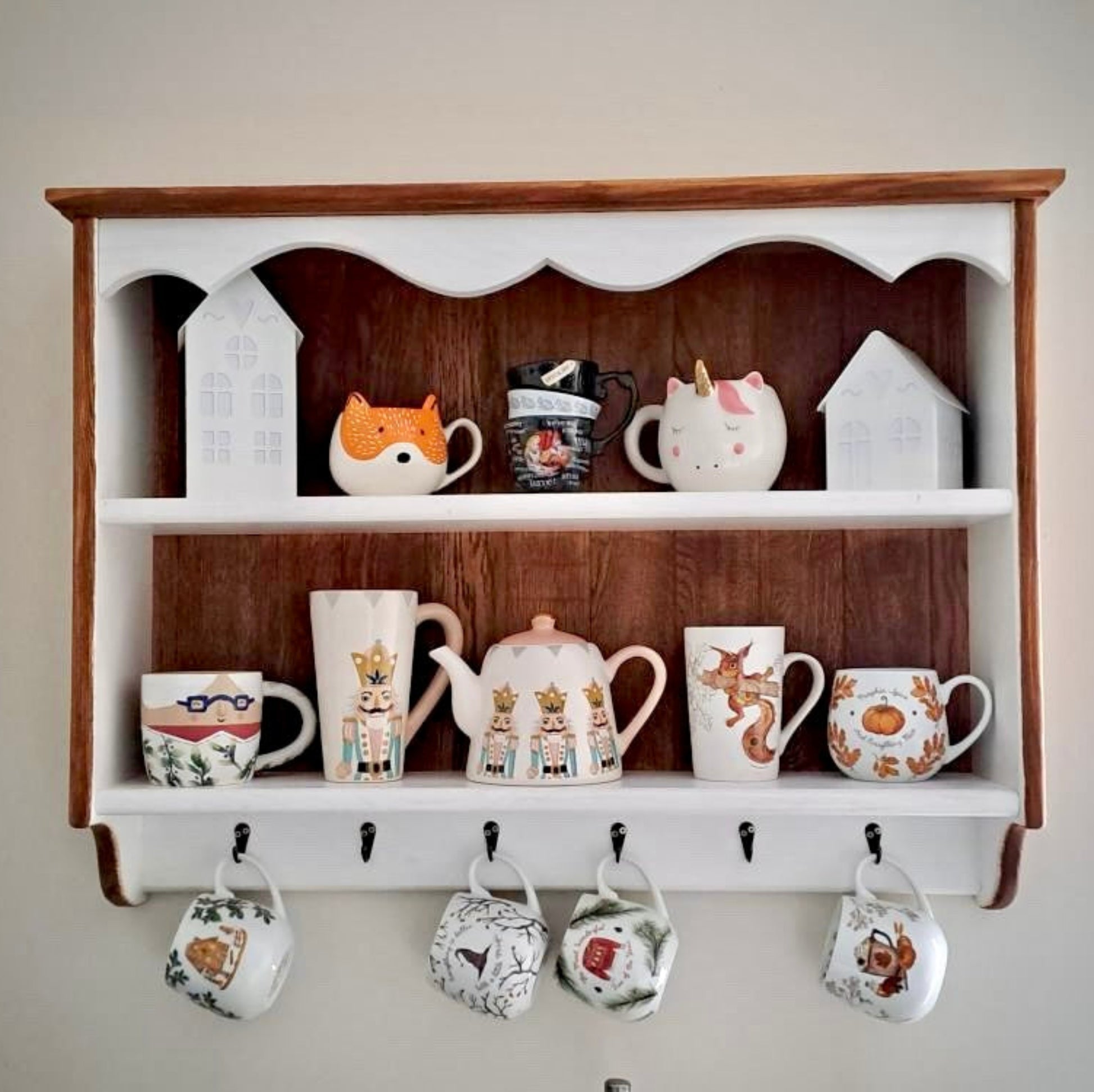Wooden shelf with decorative items including mugs and teapots on a plain wall.