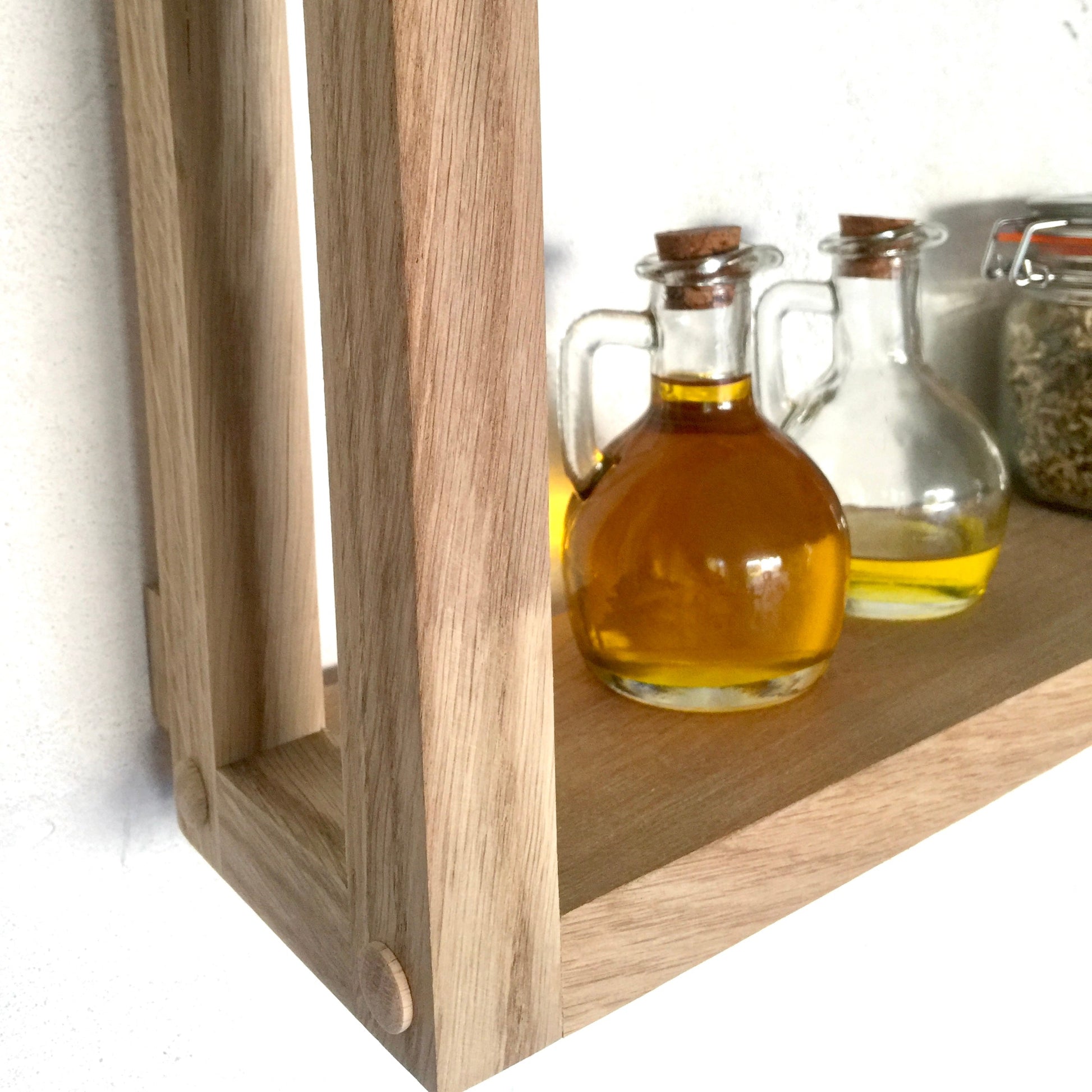 Wooden shelf with glass bottles containing liquids on a white background