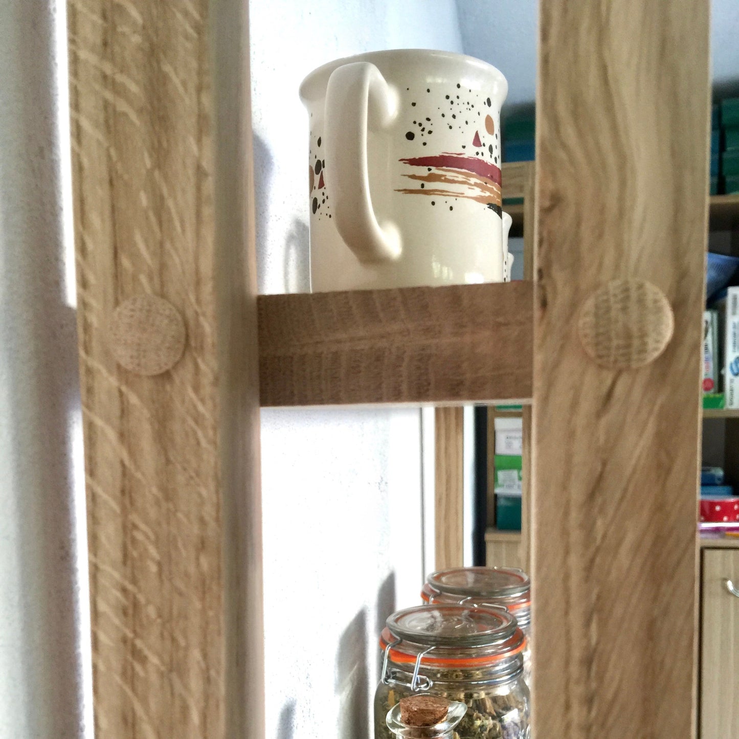 Wooden shelf with jars and a mug in a kitchen setting