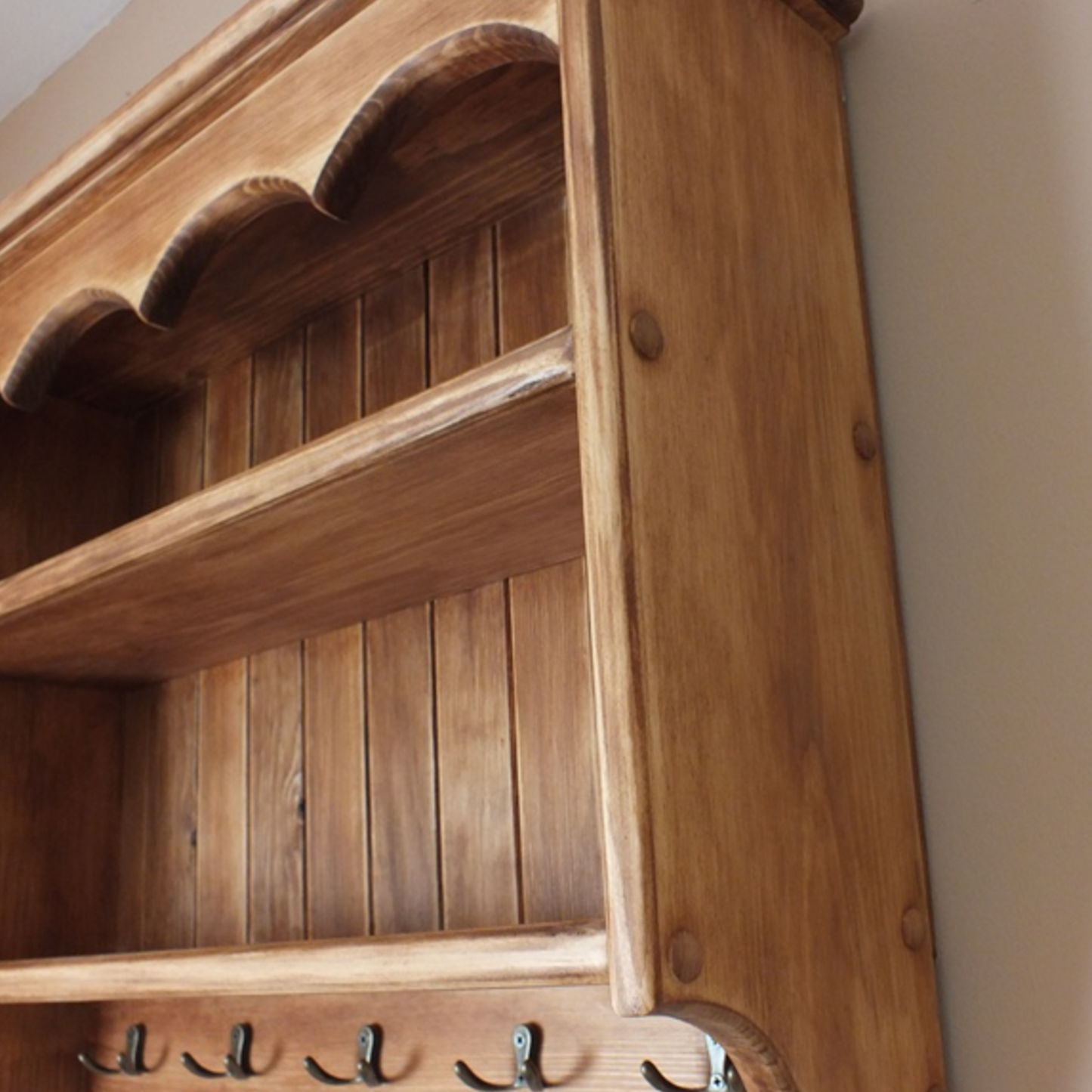 Wooden shelf with hooks against a beige wall