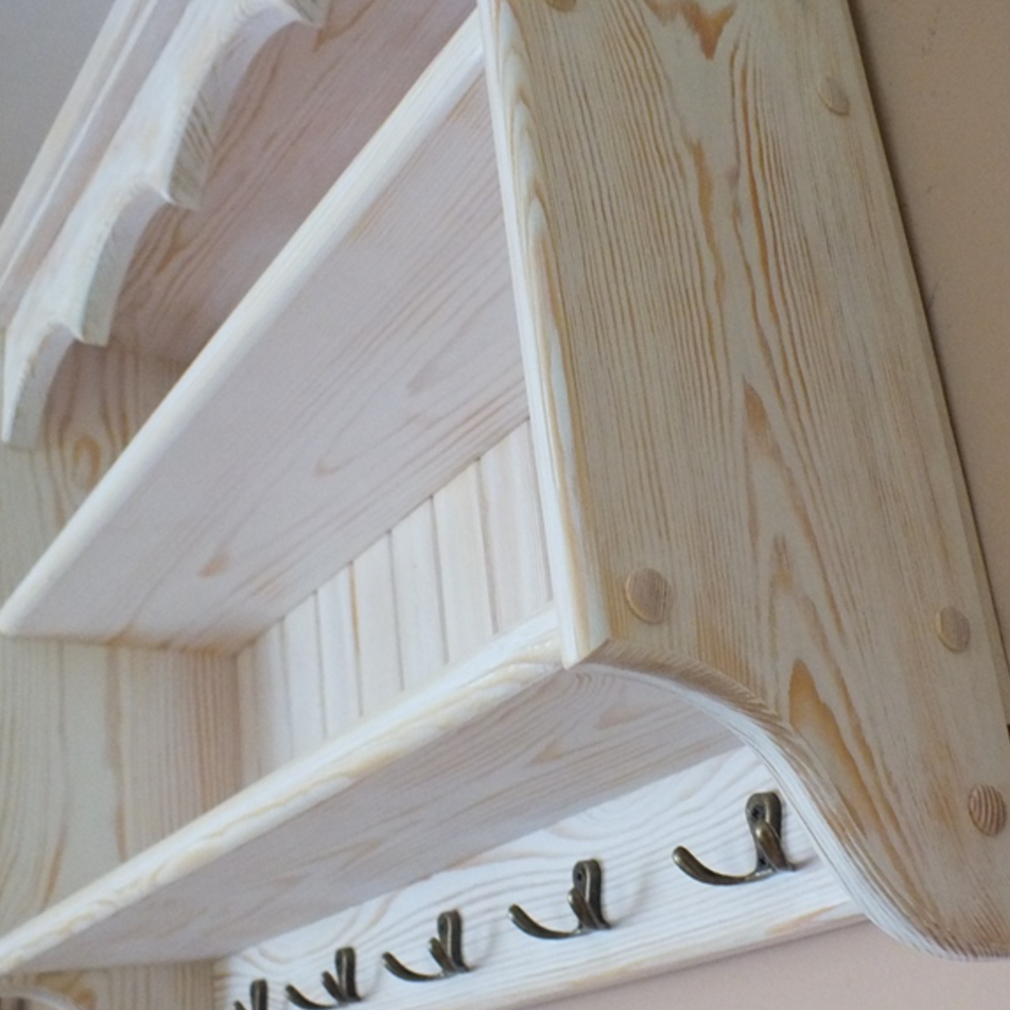 Wooden shelf with hooks against a beige wall