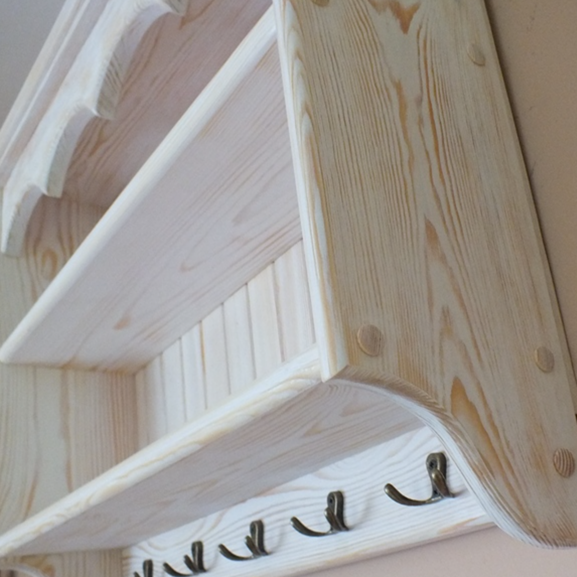 Wooden shelf with hooks against a beige wall