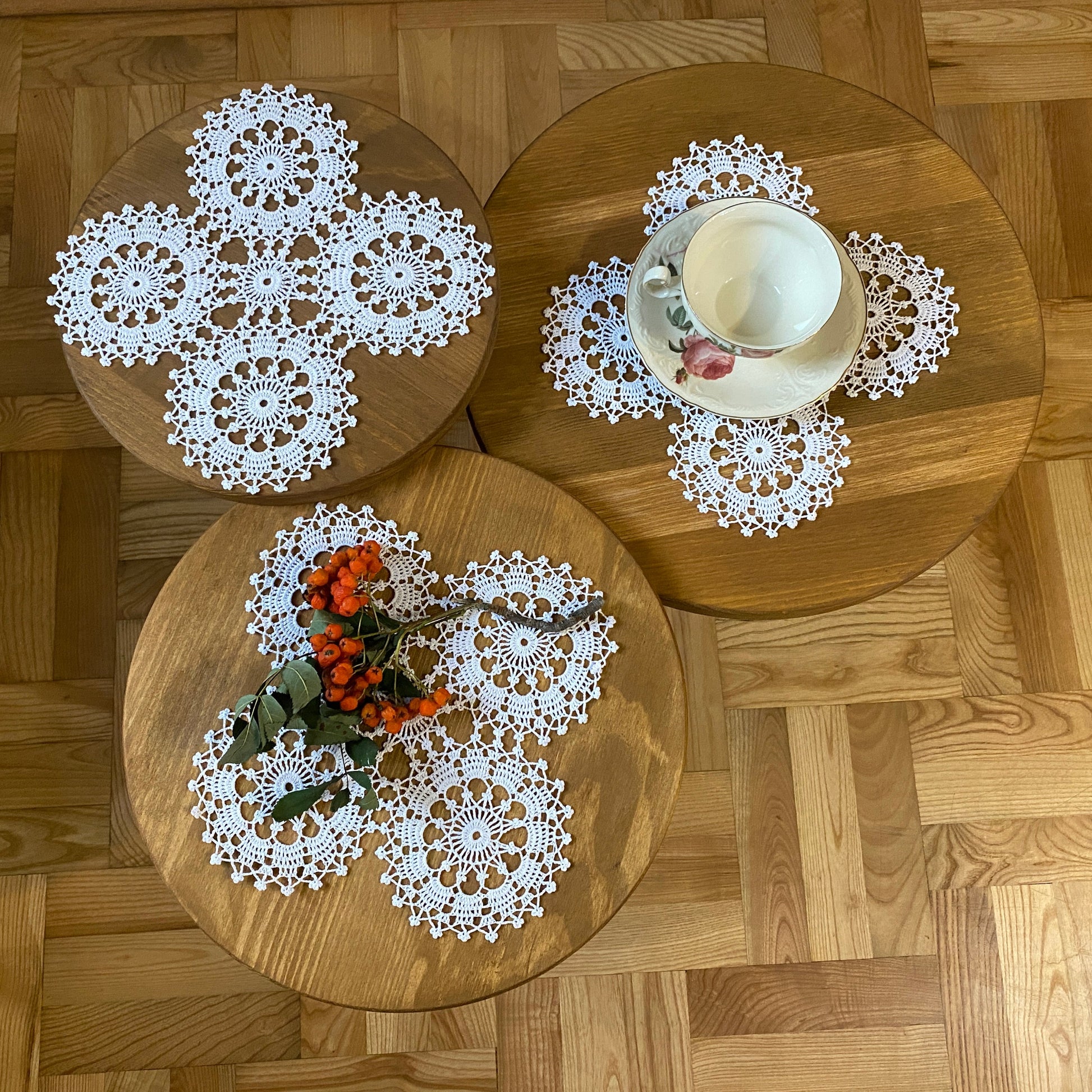 Three wooden plates with lace doilies on a wooden floor.