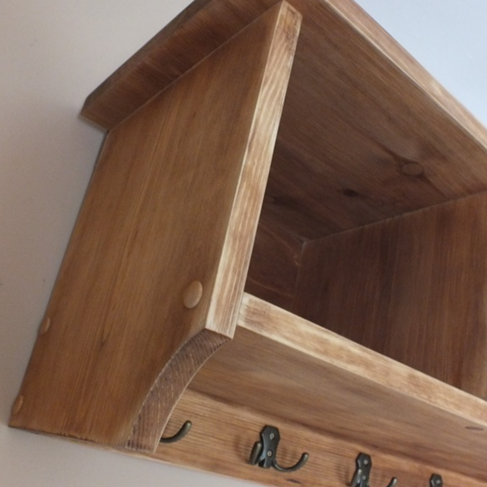 Wooden shelf with hooks on a plain background