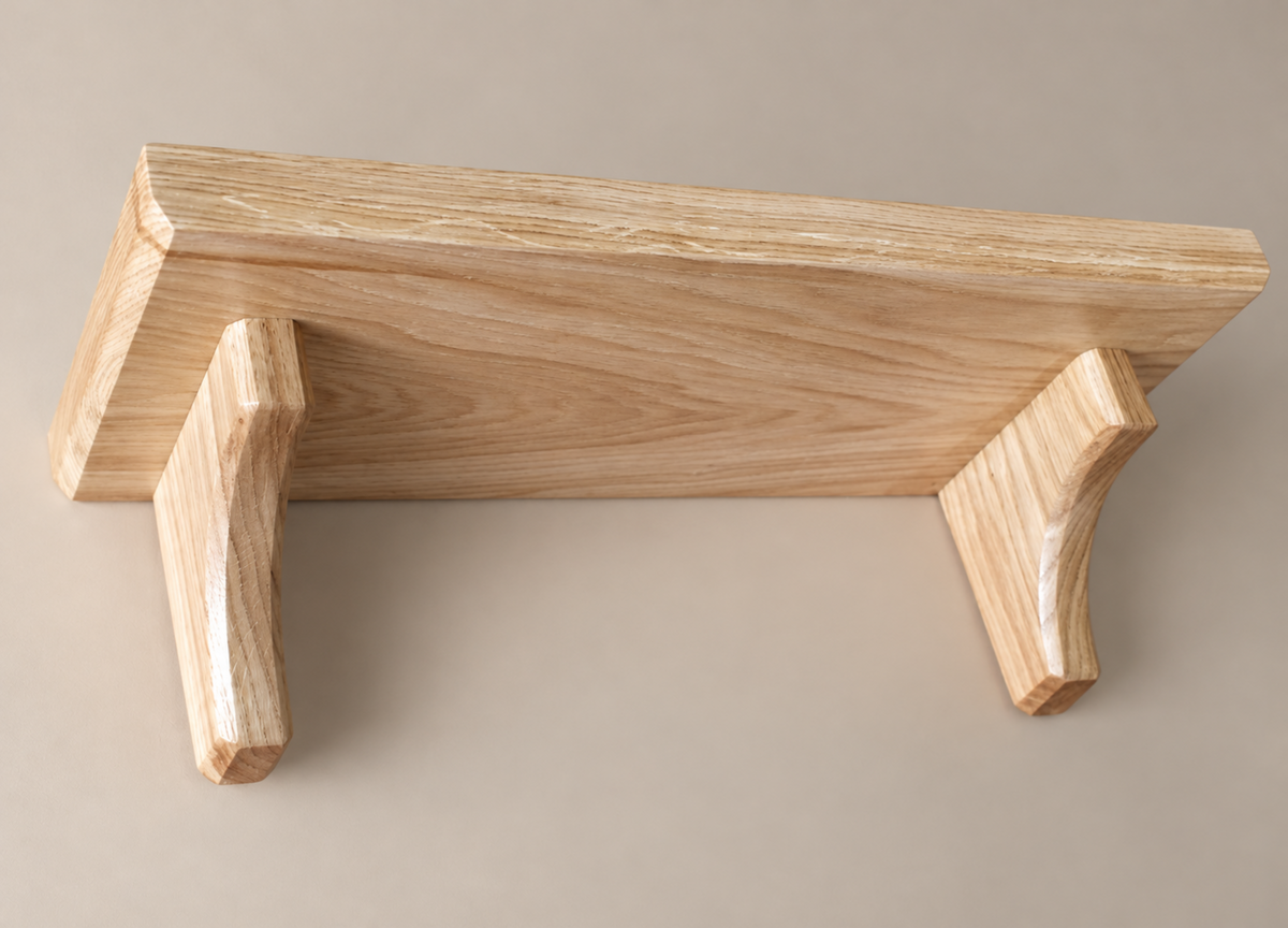 A light natural wood floating shelf with two angled support brackets, shown against a solid neutral beige background.