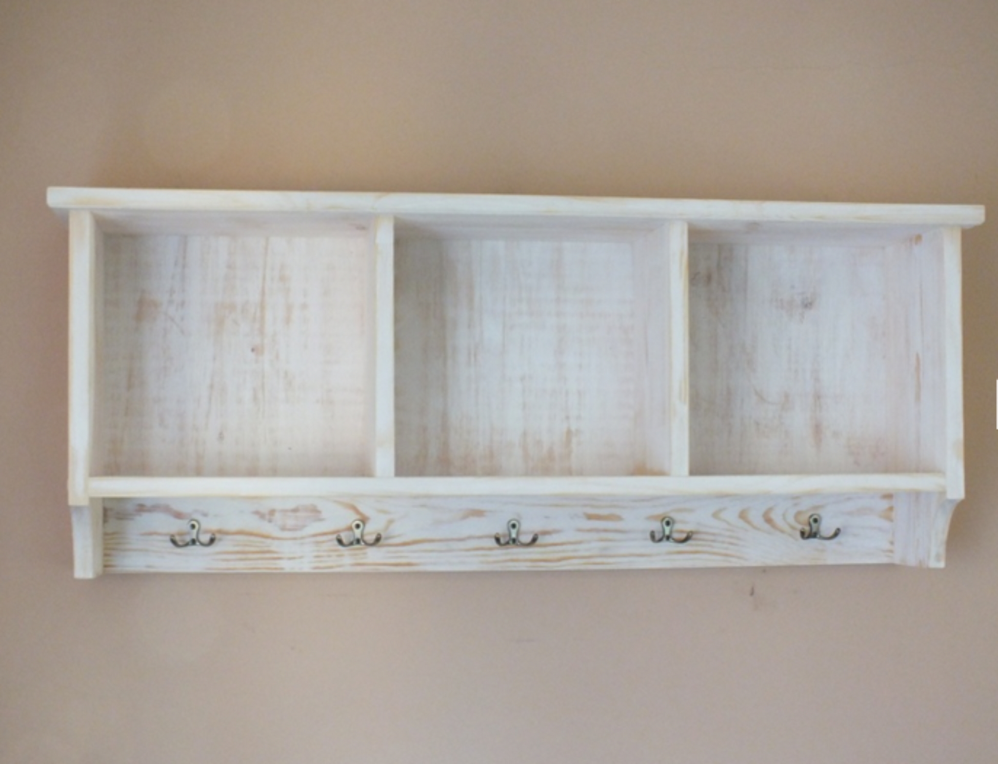 Wooden shelf with four hooks on a plain wall
