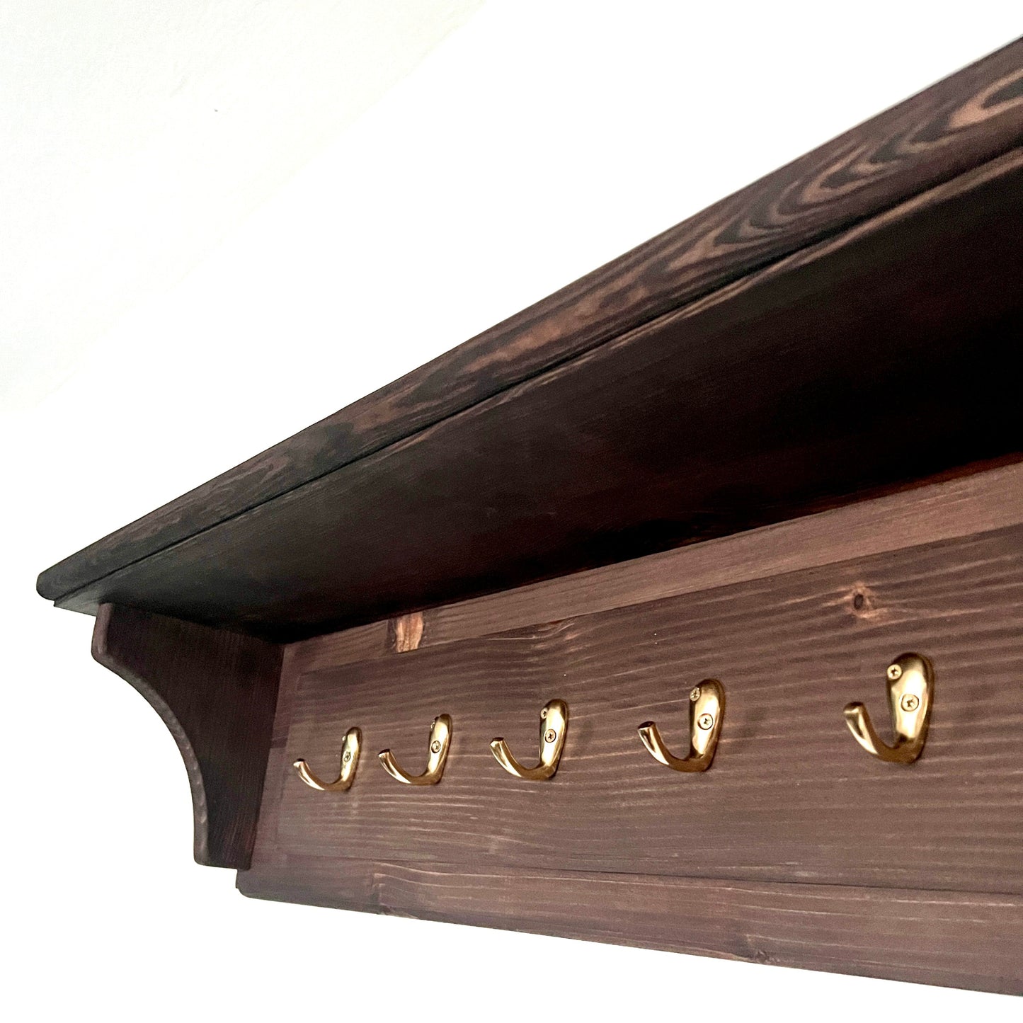 Wooden shelf with gold hooks on a white background