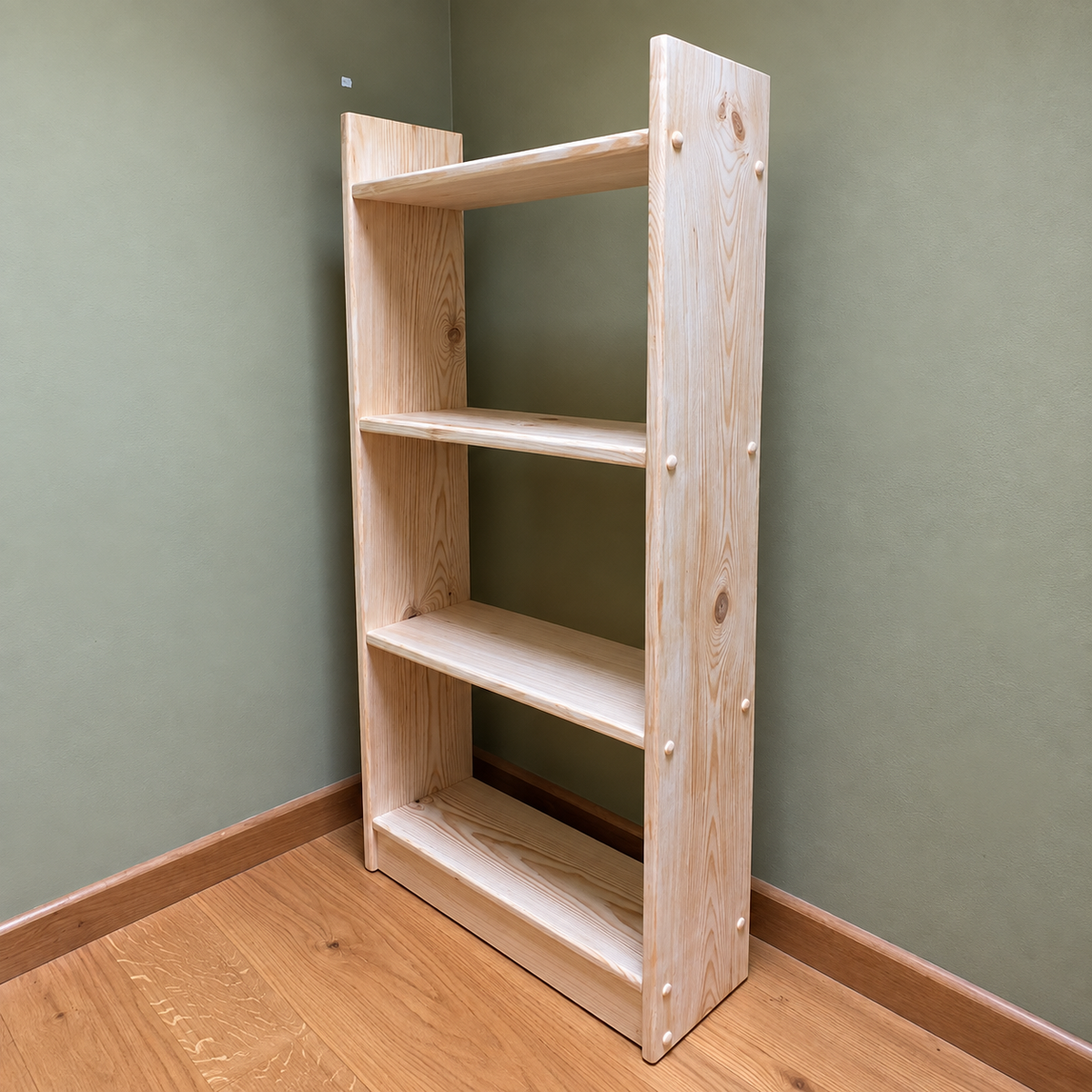 A light natural wood four-shelf bookcase with a minimalist design, photographed standing in a room corner with sage green walls and a light wood floor.
