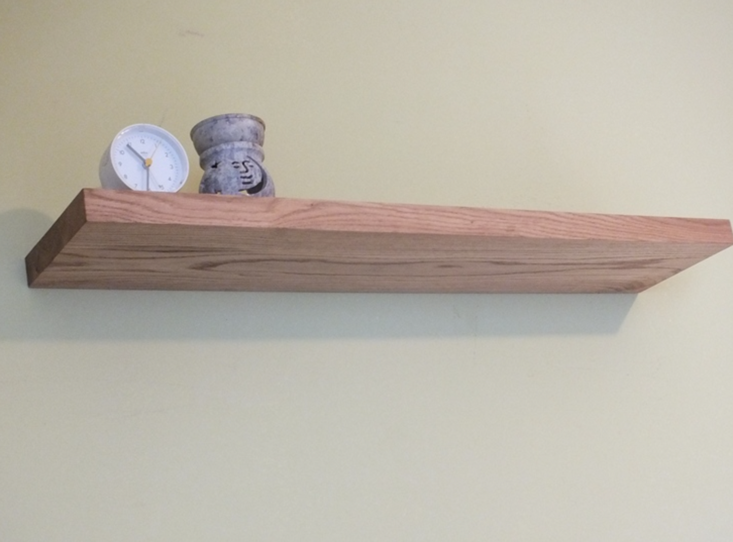 Wooden shelf with decorative items on a plain wall
