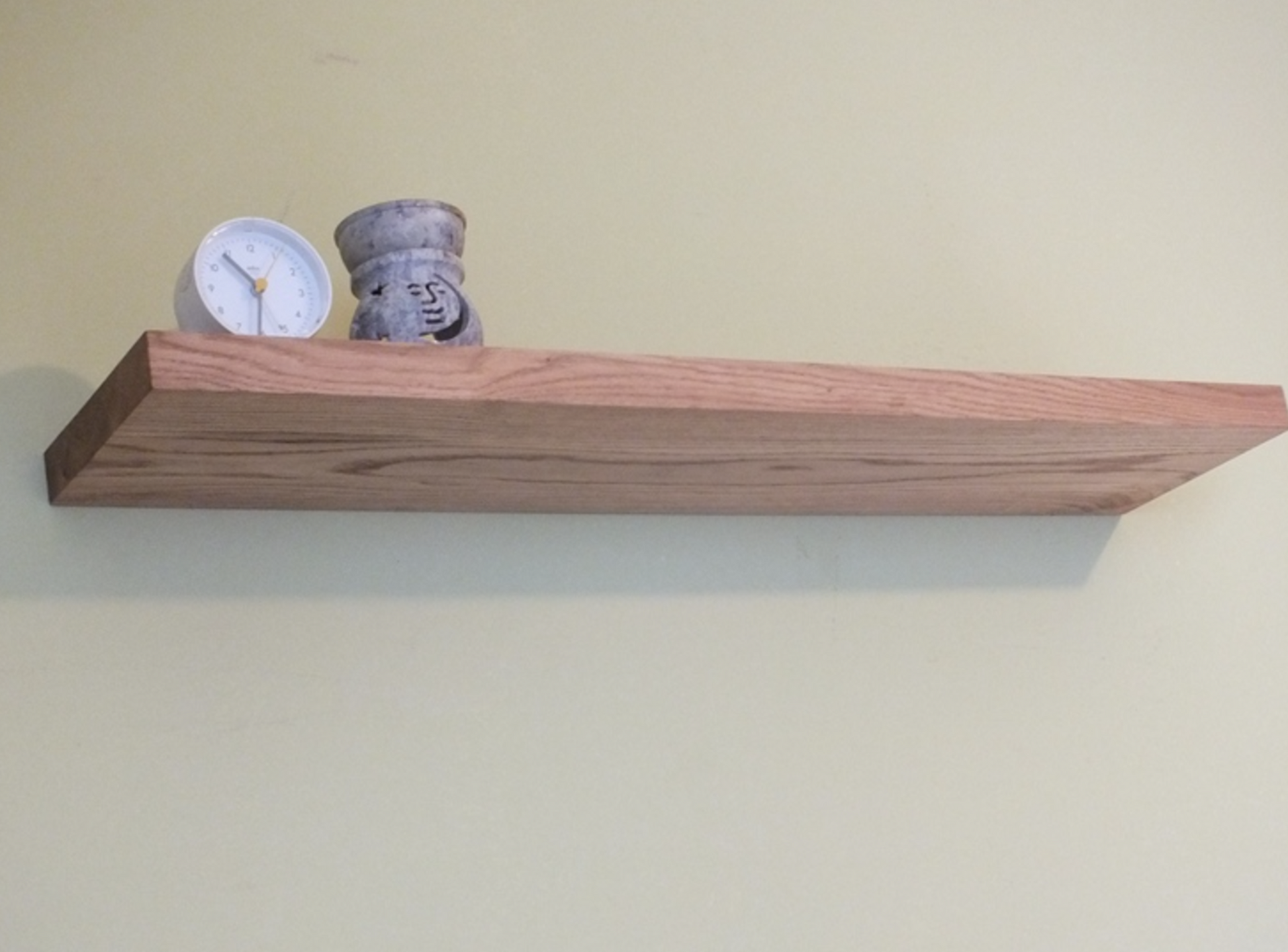 Wooden shelf with decorative items on a plain wall