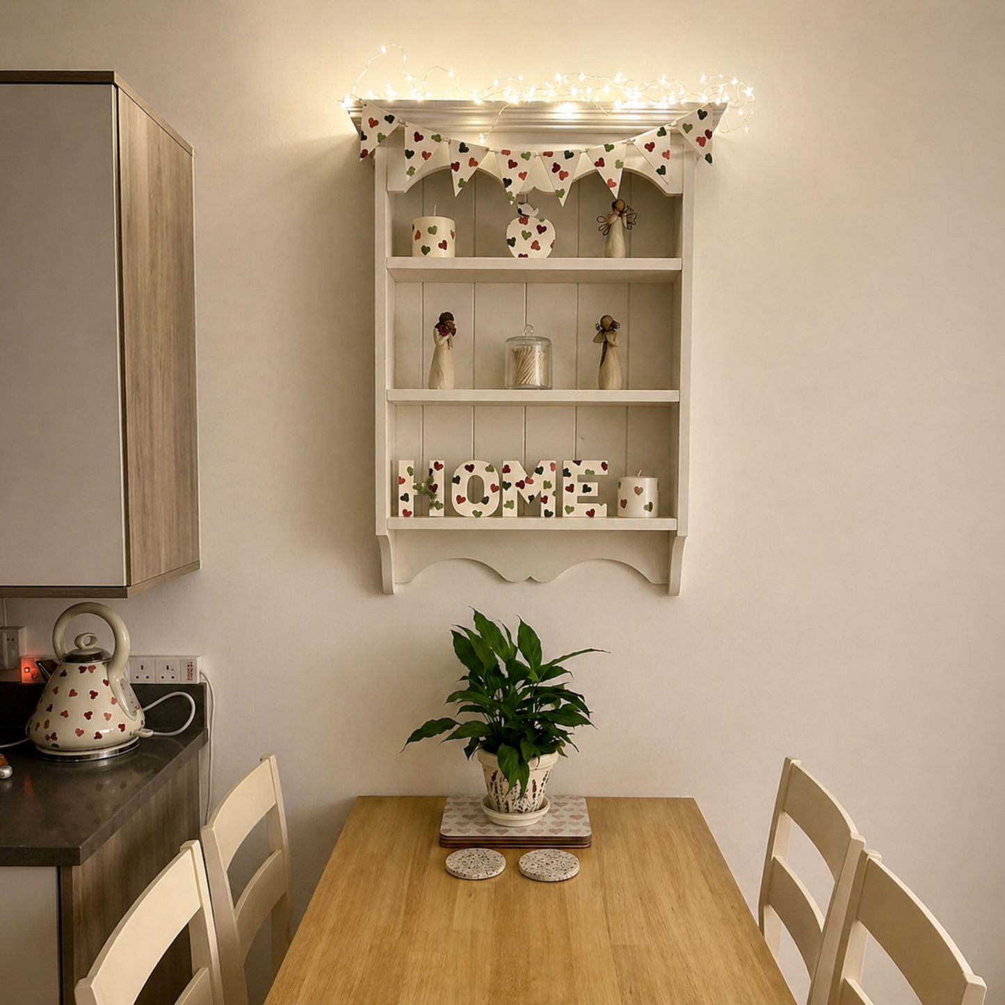 Small dining area with a wooden table, chairs, and a shelf above with decorative items.
