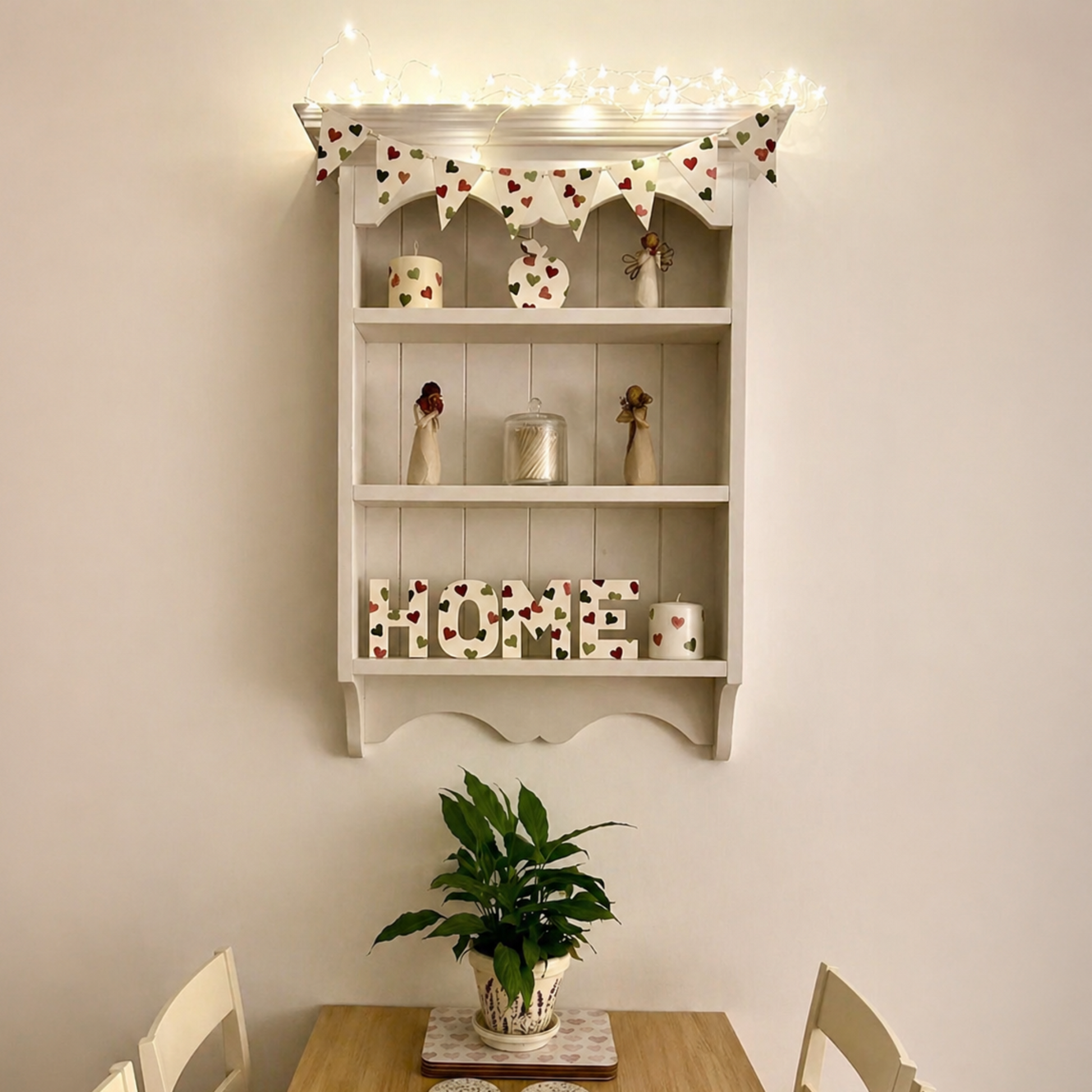 Decorative shelf with 'HOME' sign above a wooden table with a plant and coasters.