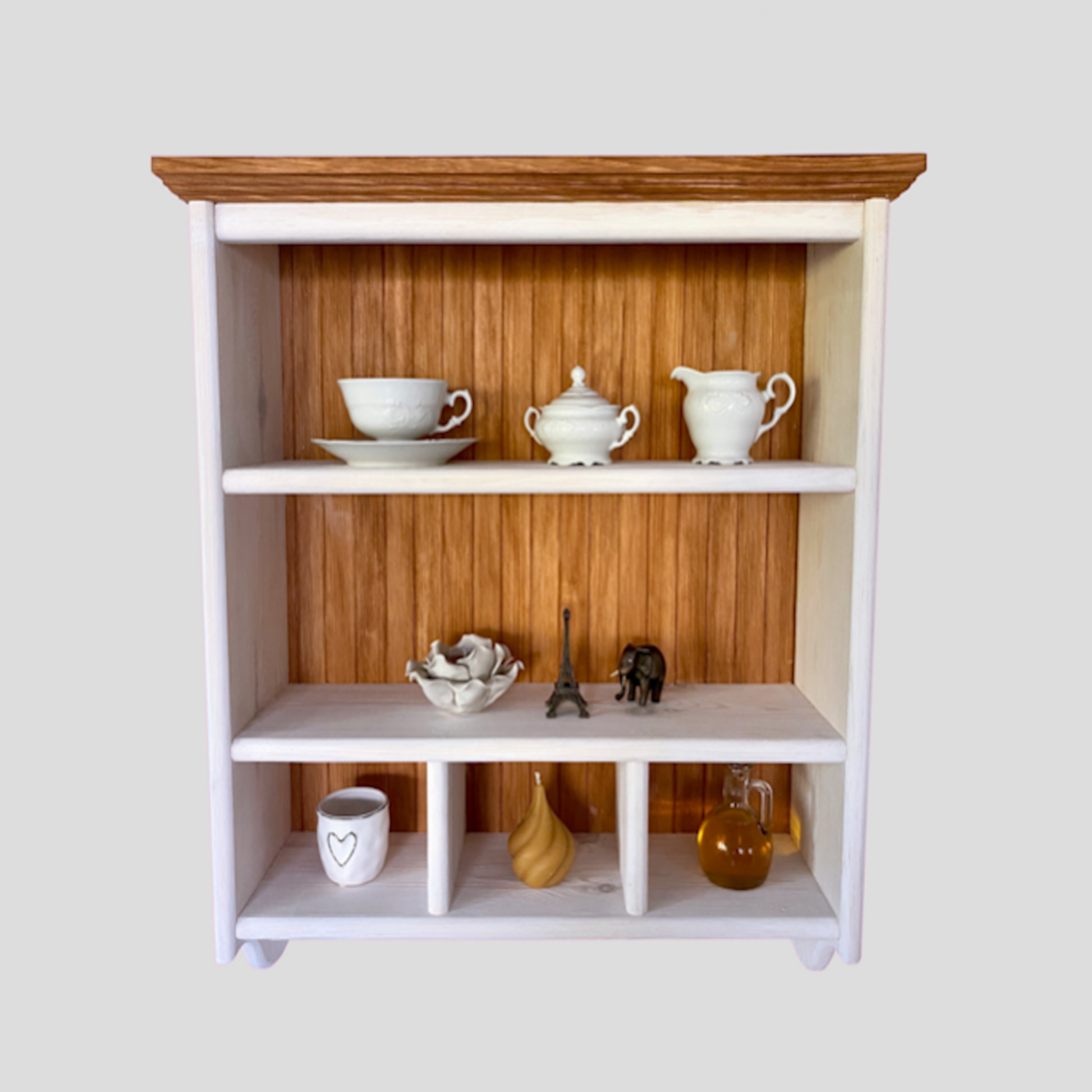 A traditional timber shelf with hangers, featuring a natural pine wood finish and divided into five shelves. It is wall-mounted with a top element depth of 20 cm and has various kitchen items placed on it, such as cups, a vase, and books.
