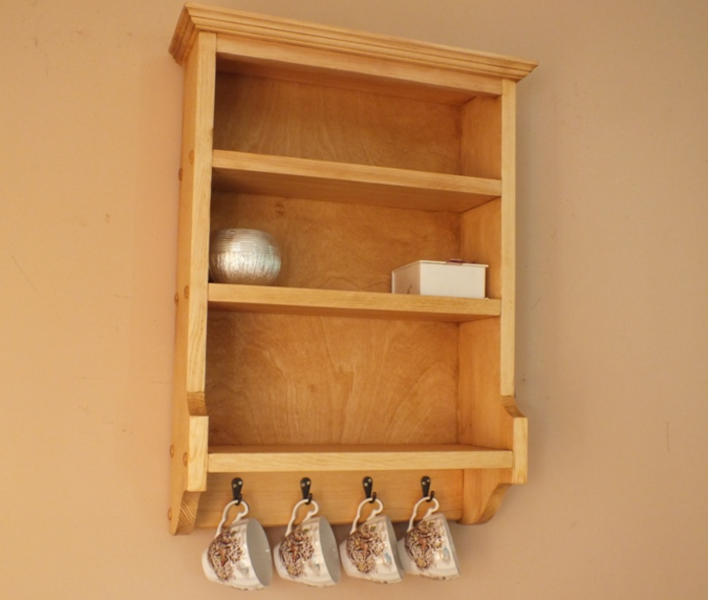 Wooden shelf with hanging mugs against a beige wall
