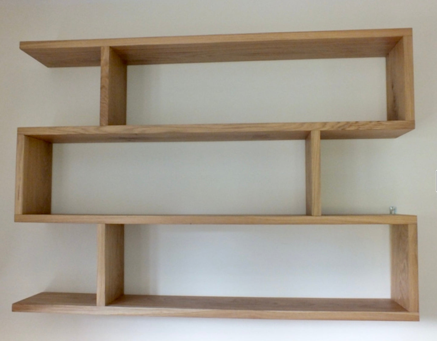 Wooden wall shelf with multiple levels against a plain background