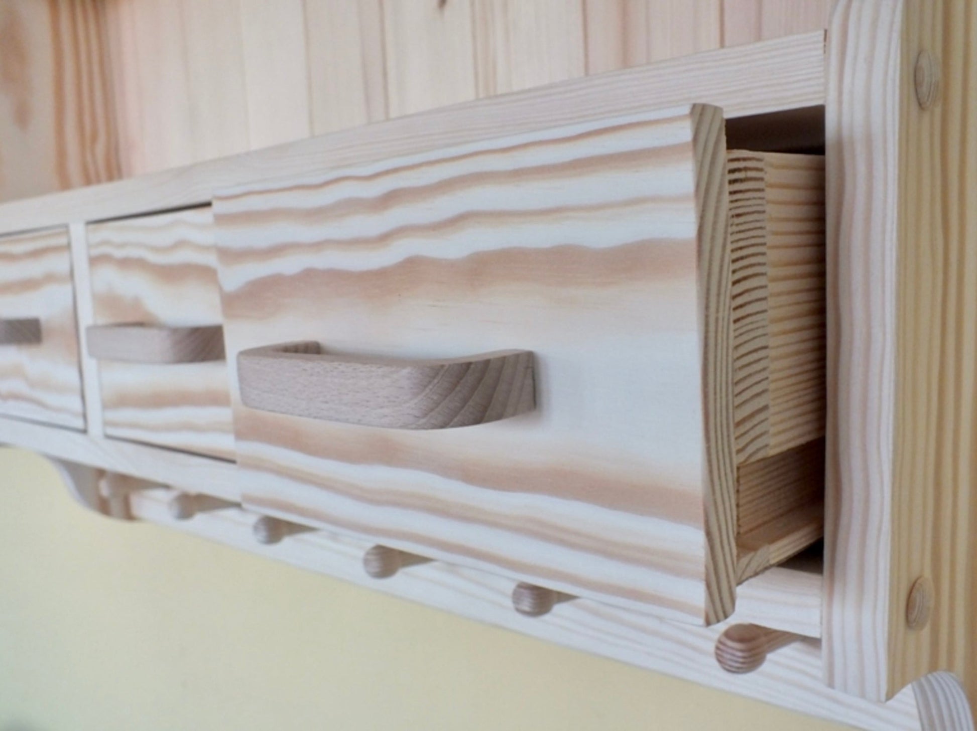 Wooden headboard with storage compartments and hooks against a wooden wall.