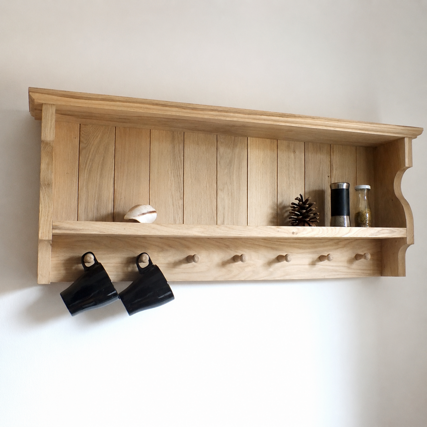 Wooden shelf with hooks and decorative items on a white wall