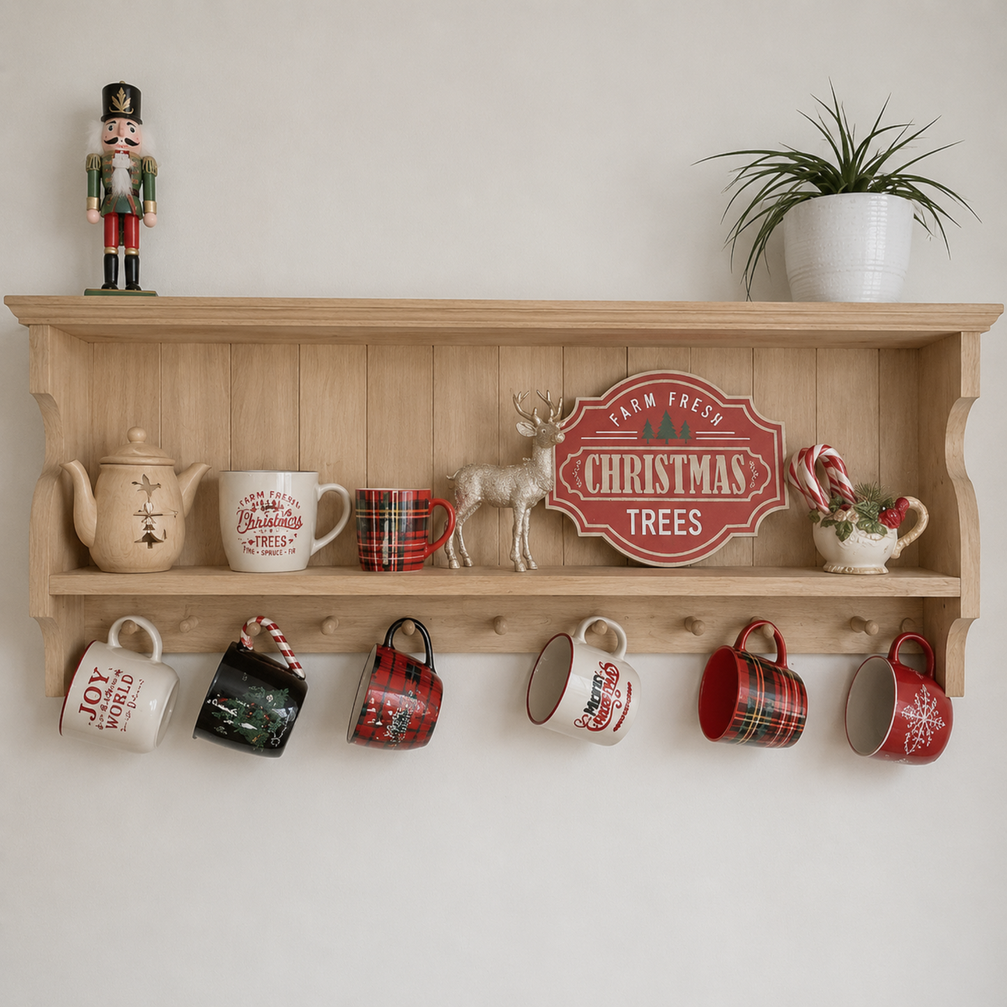 Wooden shelf with Christmas-themed decor including mugs, a teapot, and a sign.