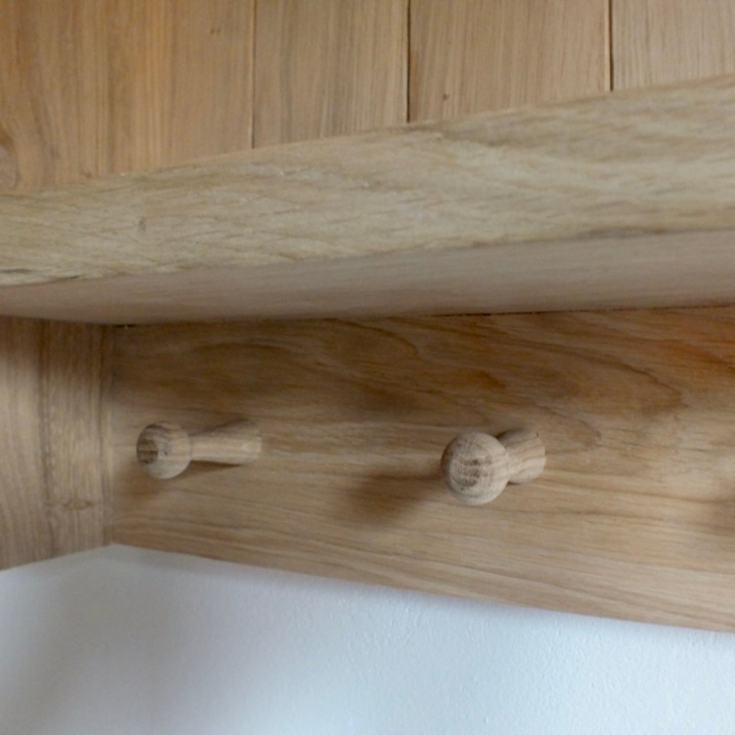 Wooden shelf with three hooks on a wooden surface