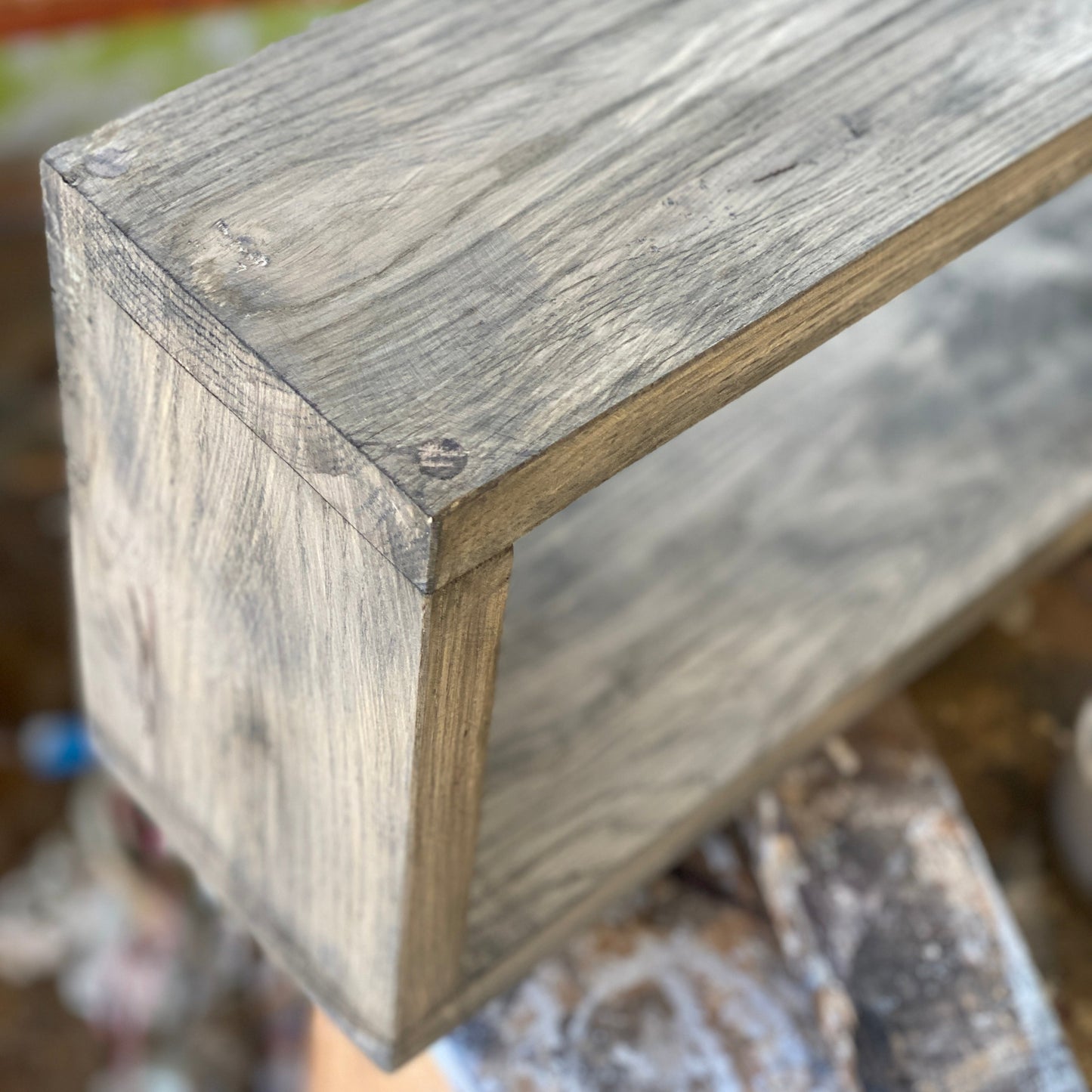 Close-up of a wooden shelf corner with a blurred background