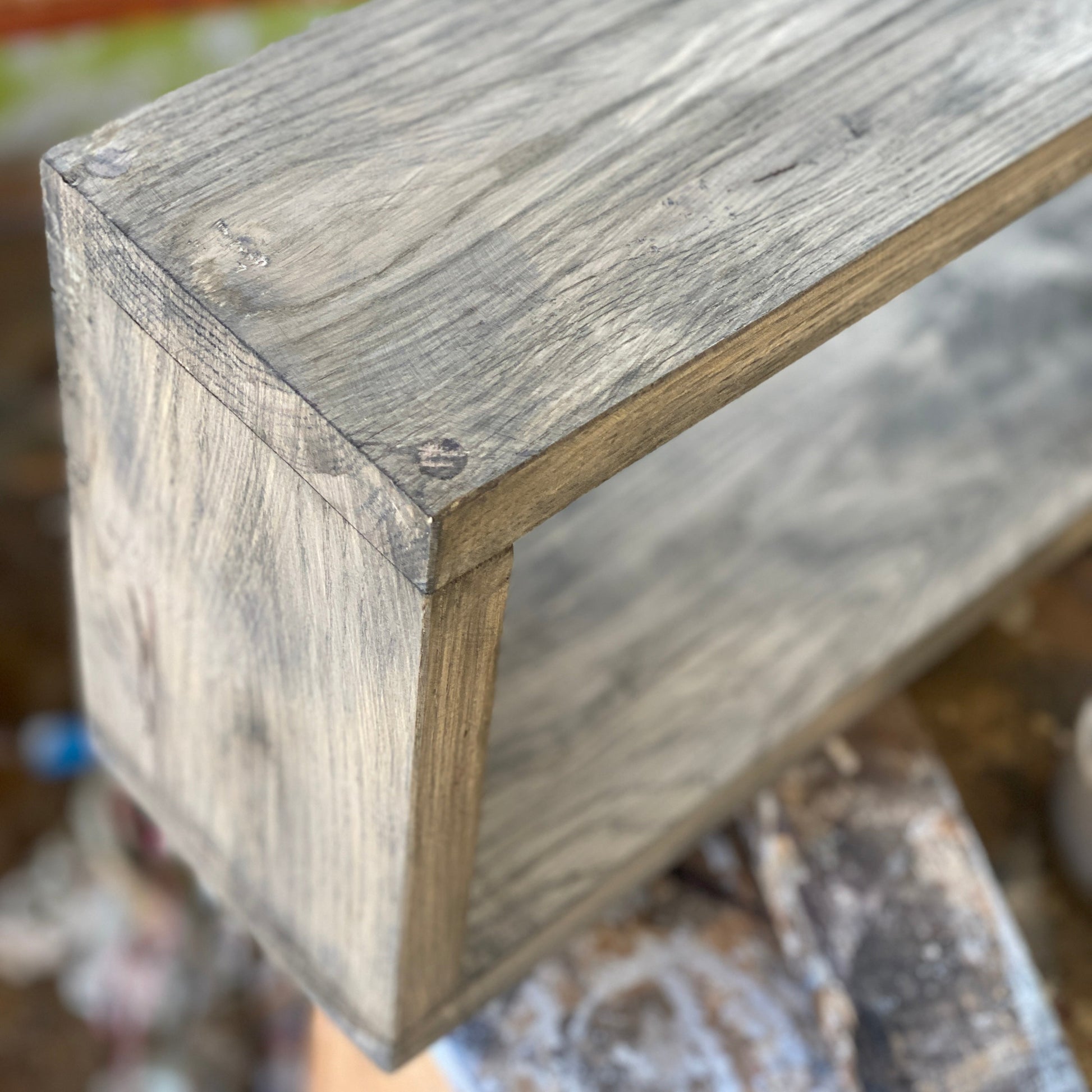 Close-up of a wooden shelf corner with a blurred background