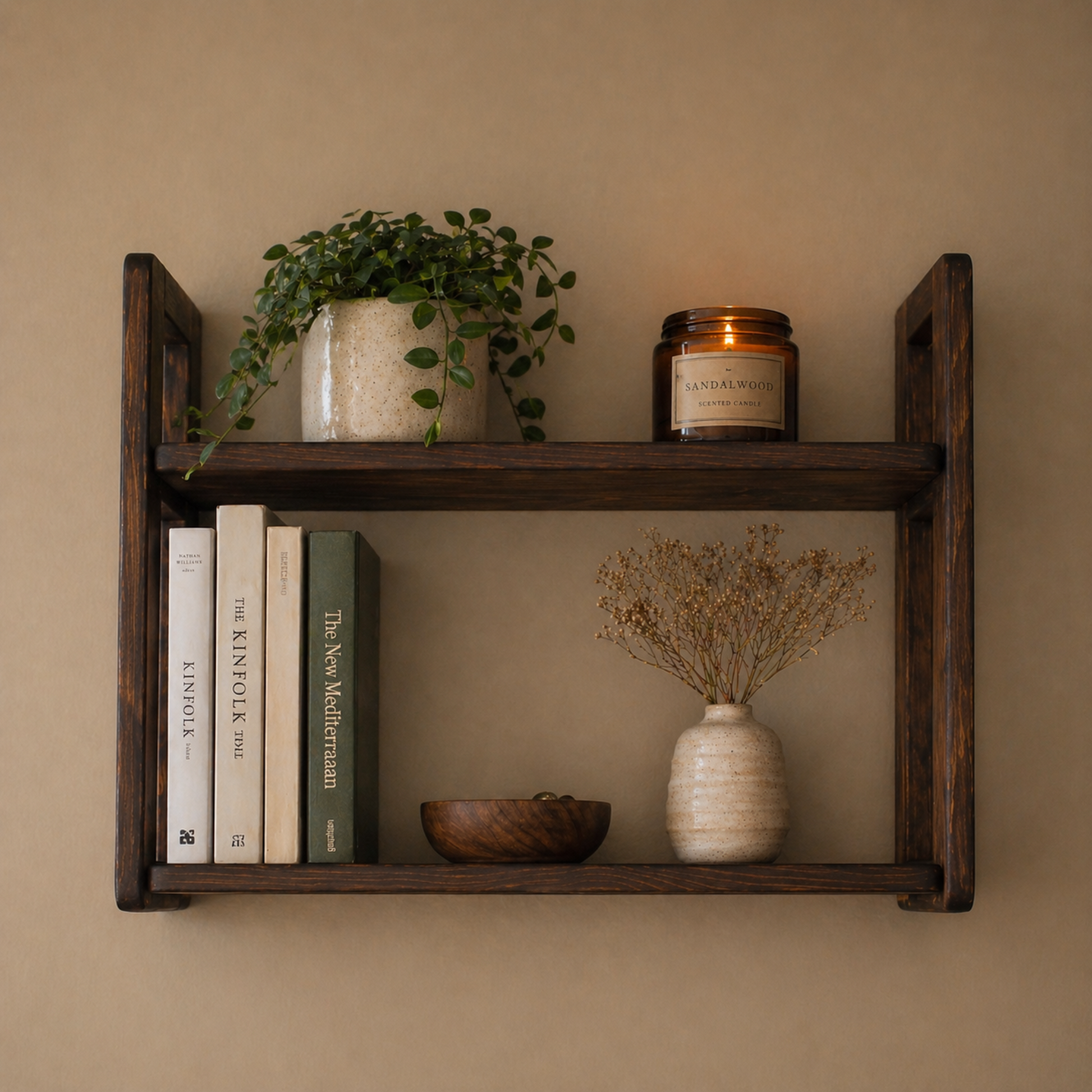 Wooden shelf with books, a plant, a candle, and decorative items against a beige wall.