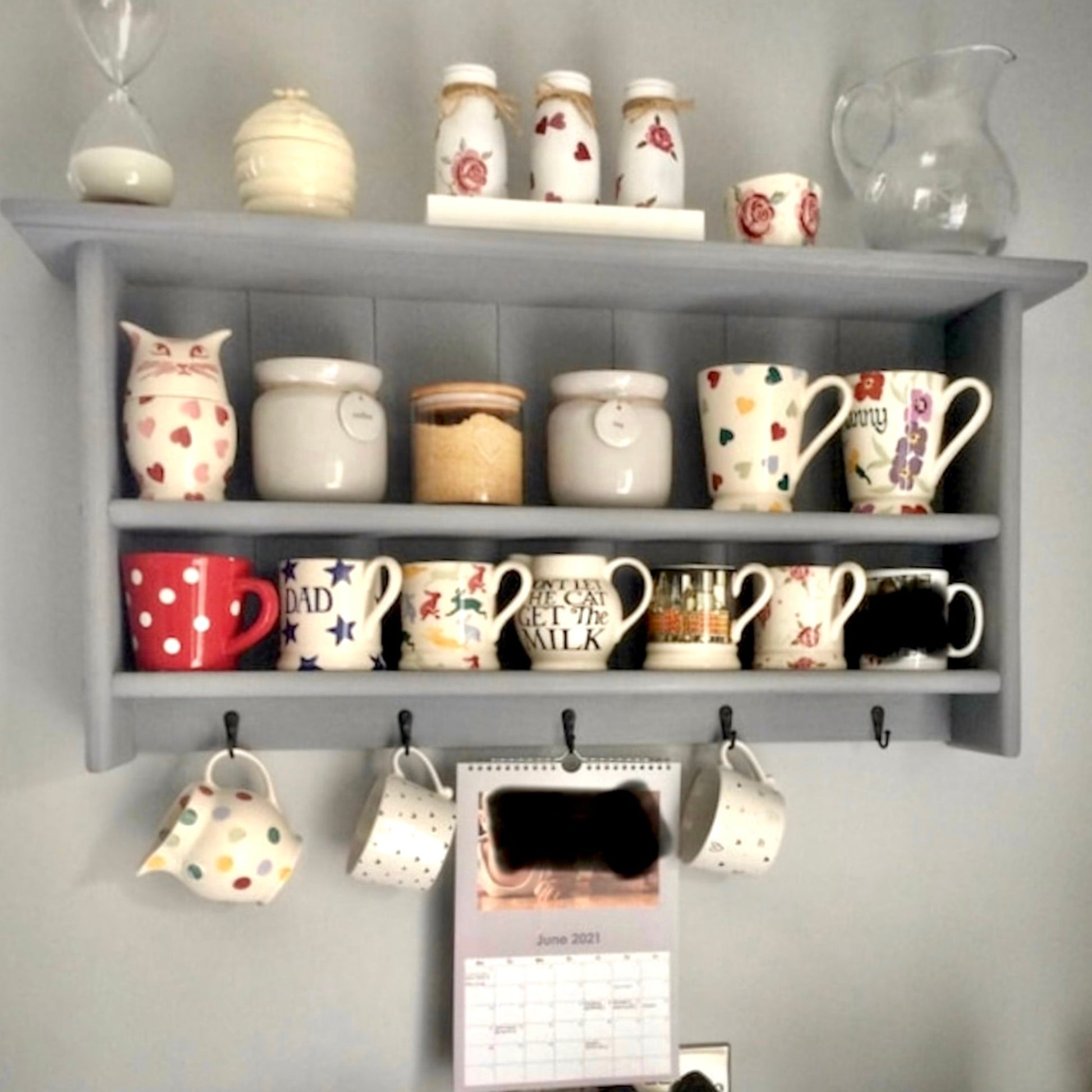 Gray shelf with various decorative items including mugs and jars on a gray wall.