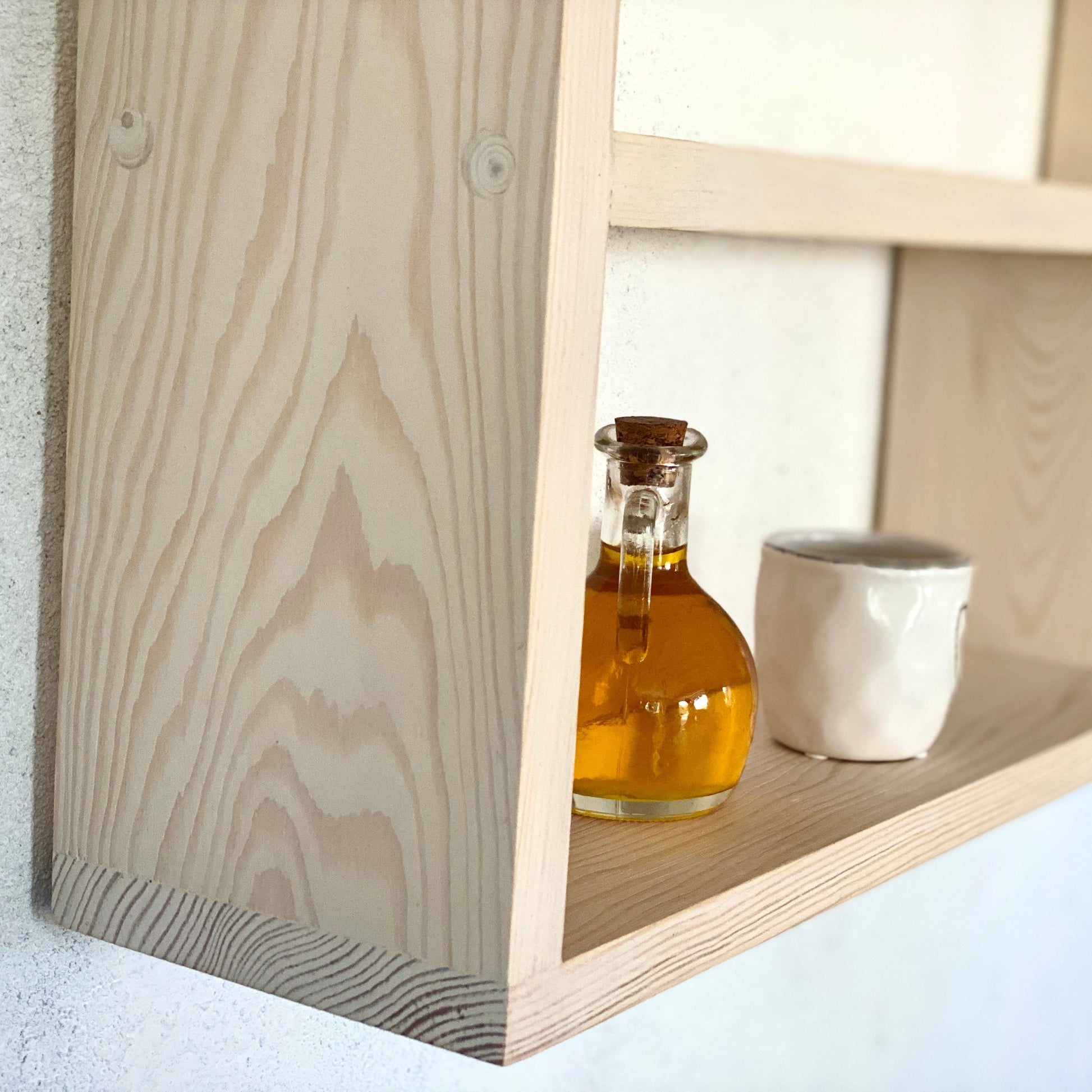 Wooden shelf with a bottle and a cup on a light background