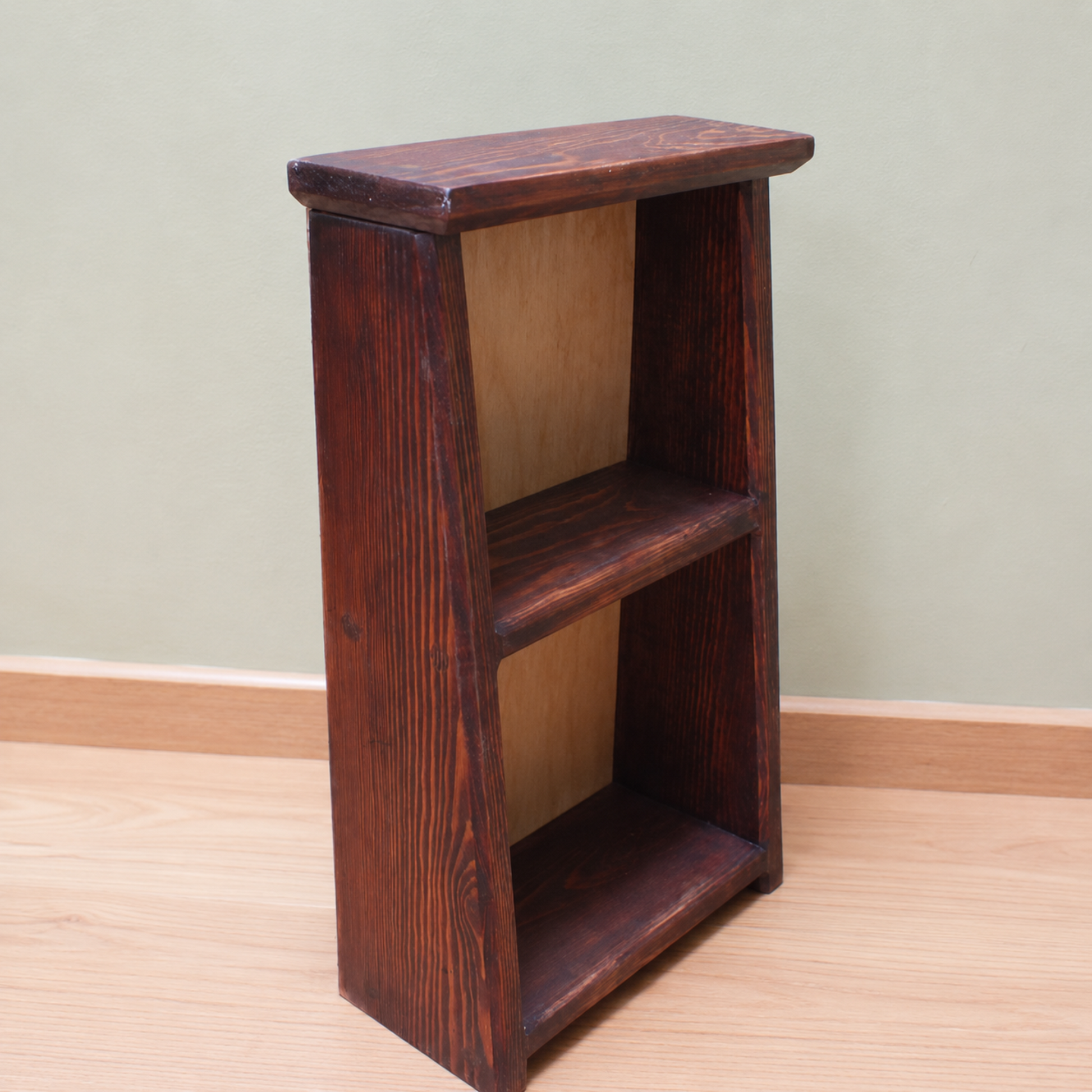 Wooden bookshelf with two shelves against a plain wall.